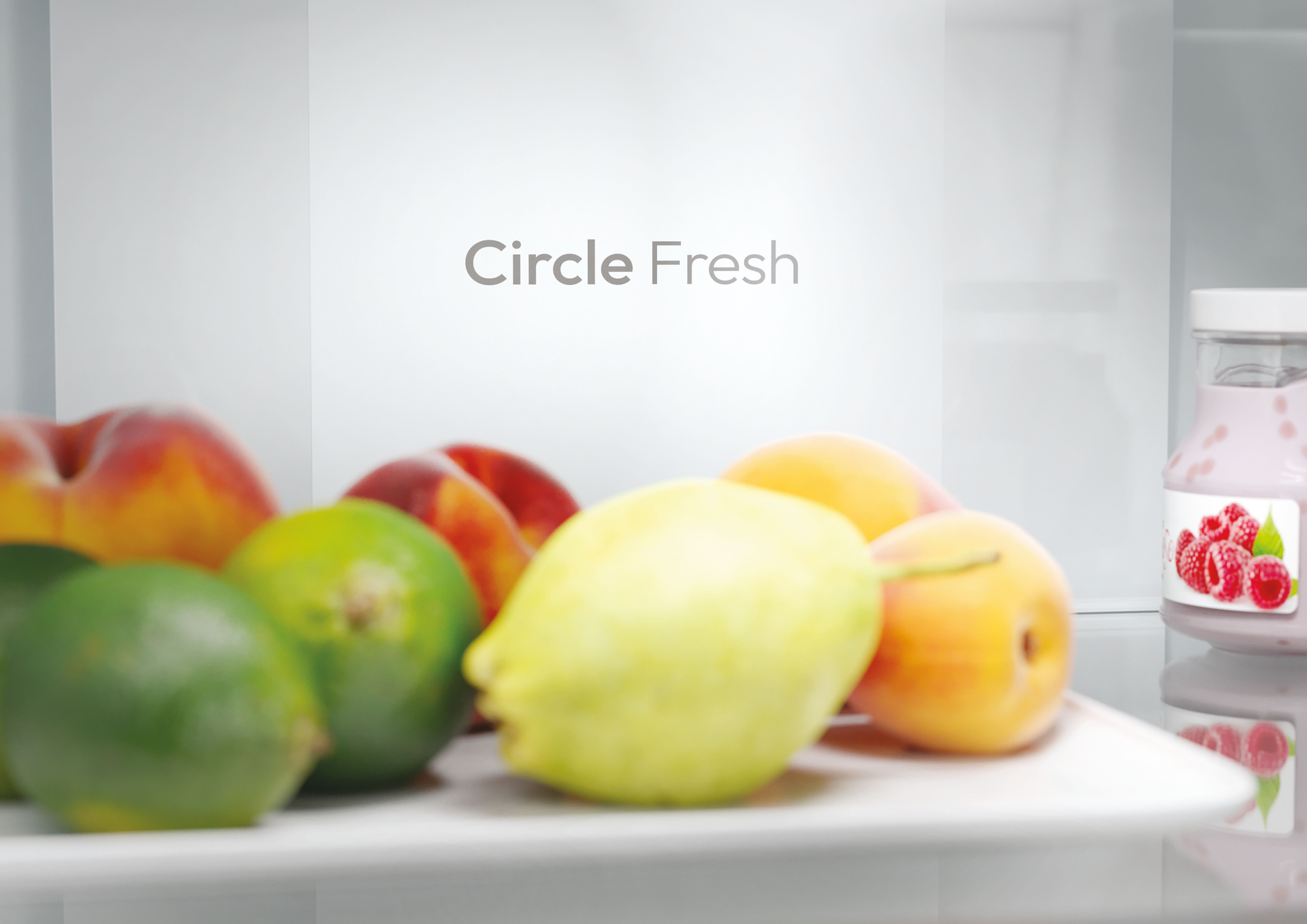 Dentro de una nevera, mostrando frutas y un frasco de yogur. El texto en la pared dice 'Circle Fresh'.