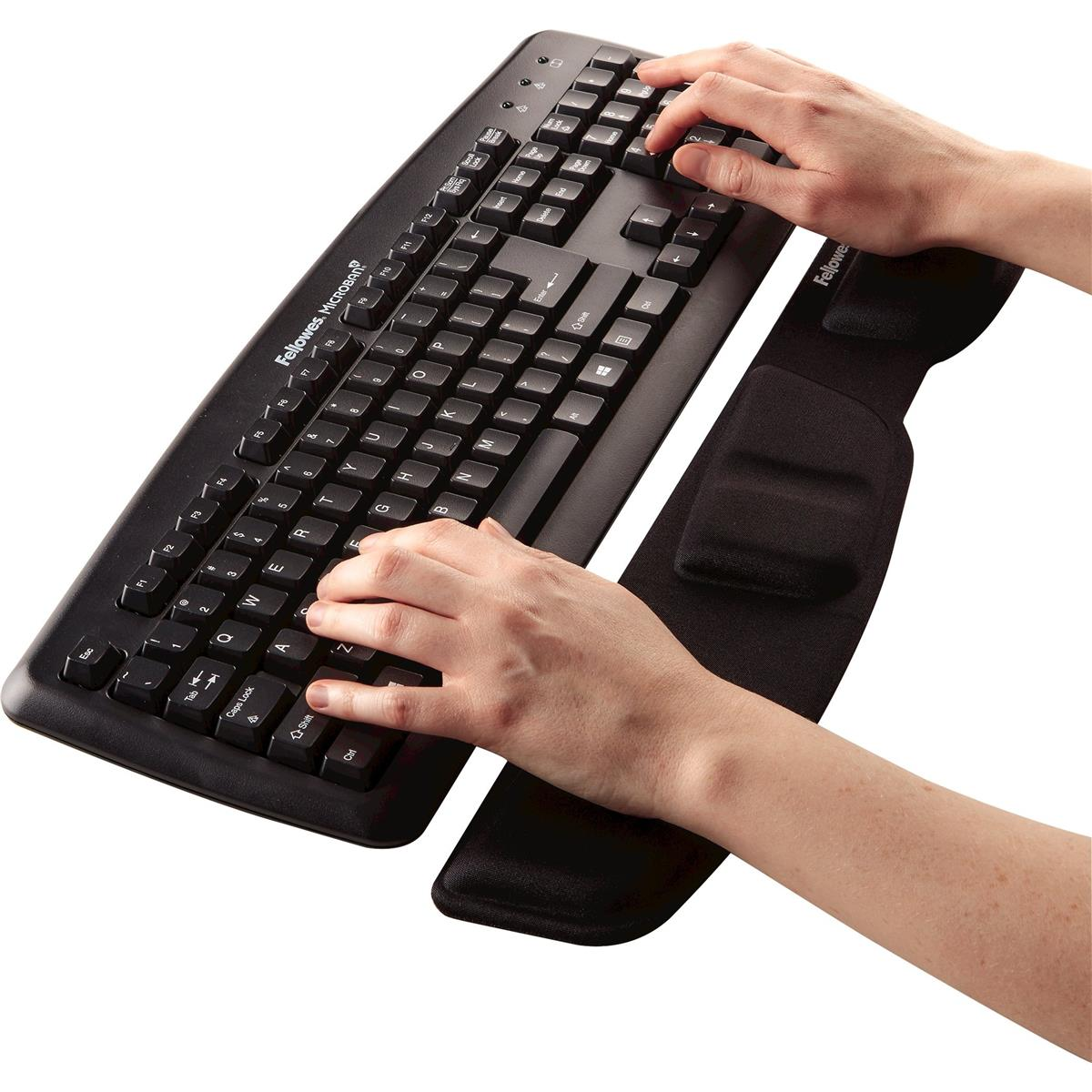 Hände, die auf einer schwarzen Tastatur mit Handgelenkauflage tippen.