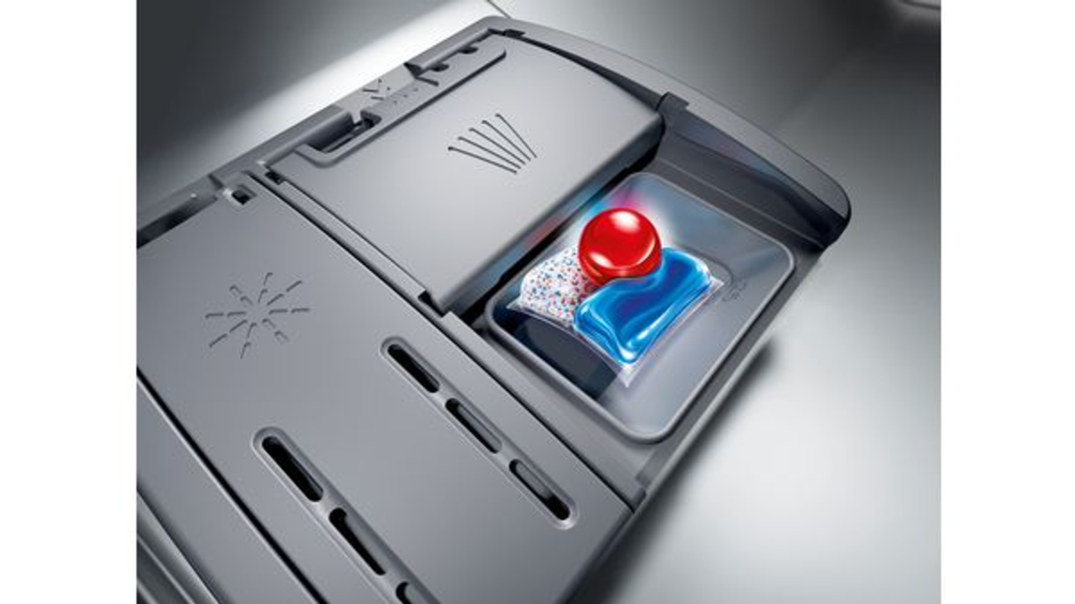Cápsula de detergente para lavavajillas dentro de un dispensador, con cápsula roja y azul.