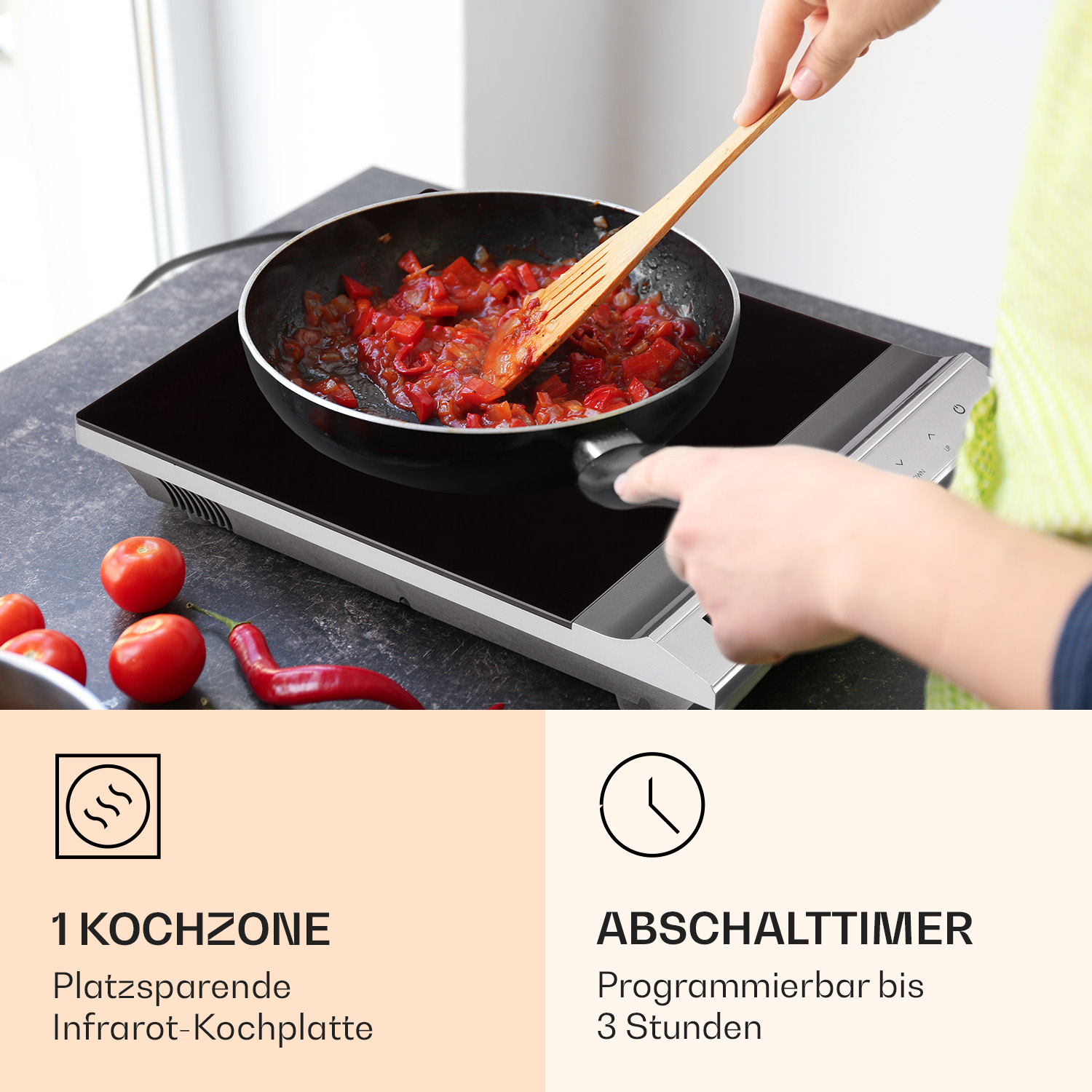 Ein Induktionskochfeld mit einer Pfanne, die rote Sauce kocht, neben Tomaten. Eine Hand zeigt.