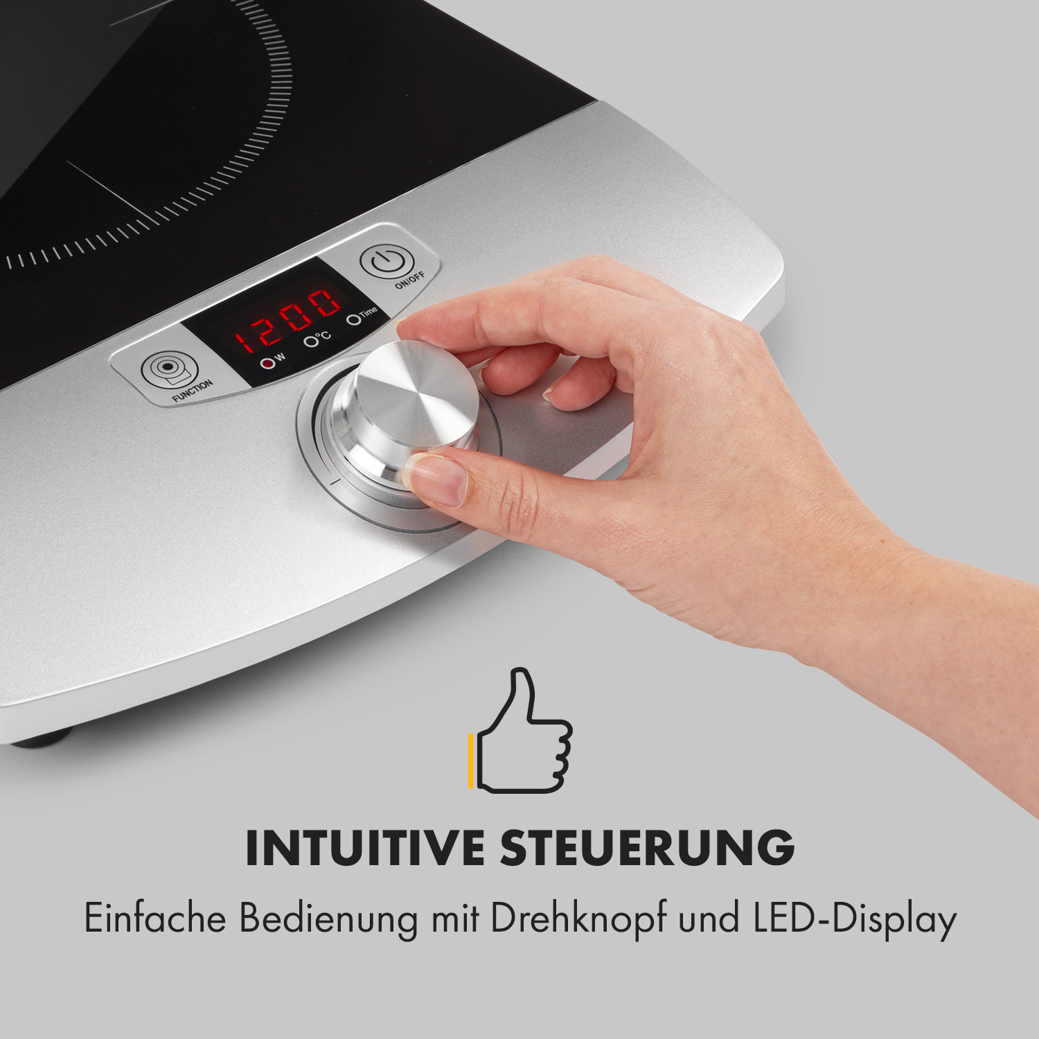 Hand einer Person, die einen Drehregler auf einem silbernen Induktionskochfeld einstellt.