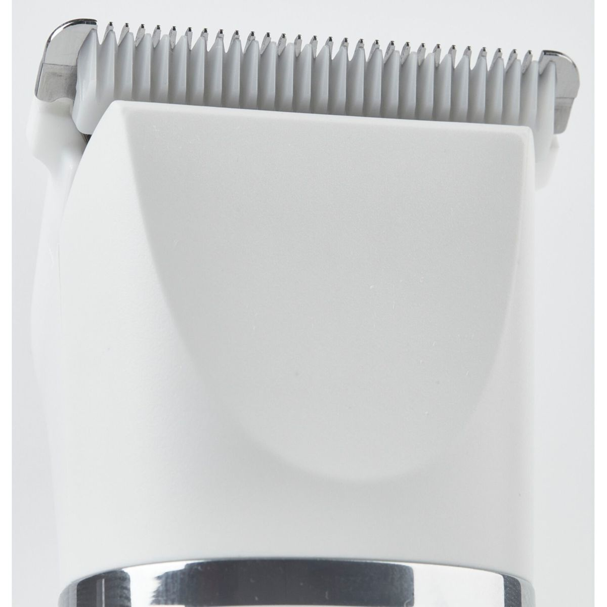 Zbliżenie białej głowicy trymera do włosów ze srebrnymi ostrzami na białym tle.