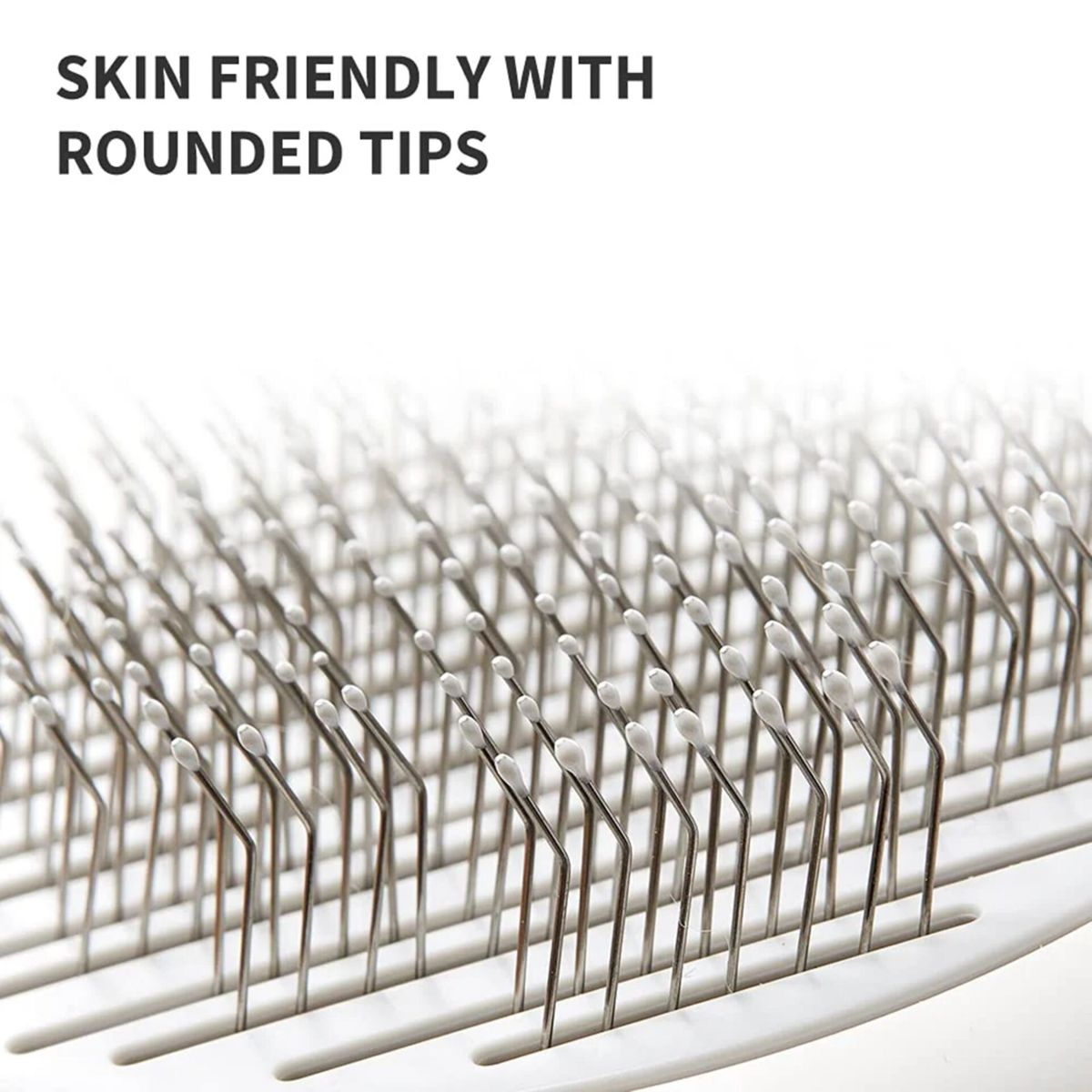 Zbliżenie szczotki do pielęgnacji zwierząt z wieloma metalowymi szpilkami i białymi końcówkami na białym tle.