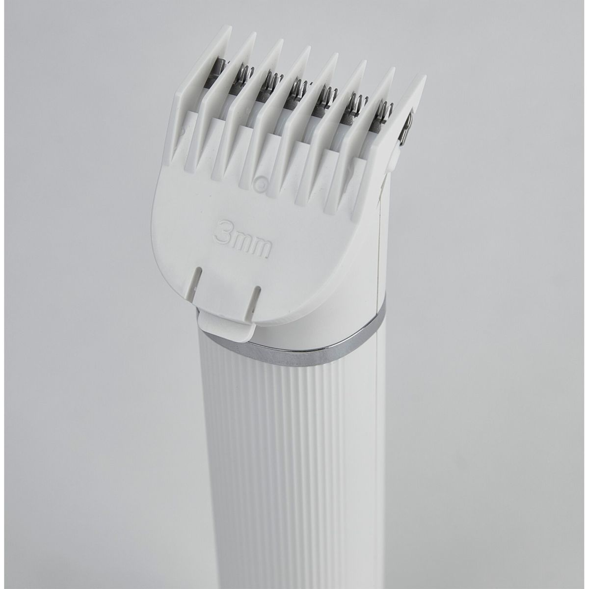 Zbliżenie białej maszynki do włosów z prowadnicą 3 mm. Obudowa biała, ostrza srebrne i białe.