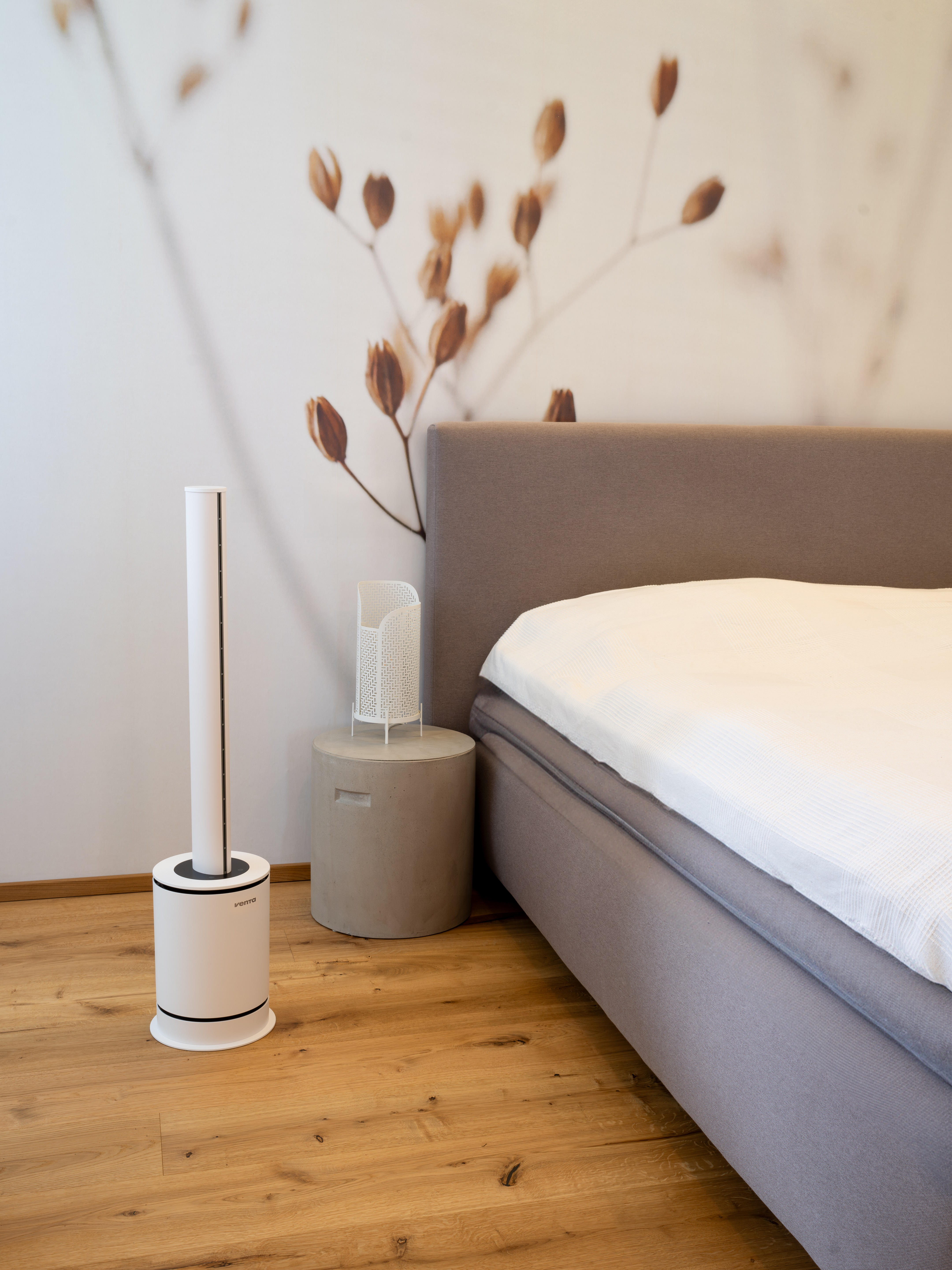 Schlafzimmer: moderner hoher Ventilator, Beistelltisch und Bett mit neutralem Kopfteil.