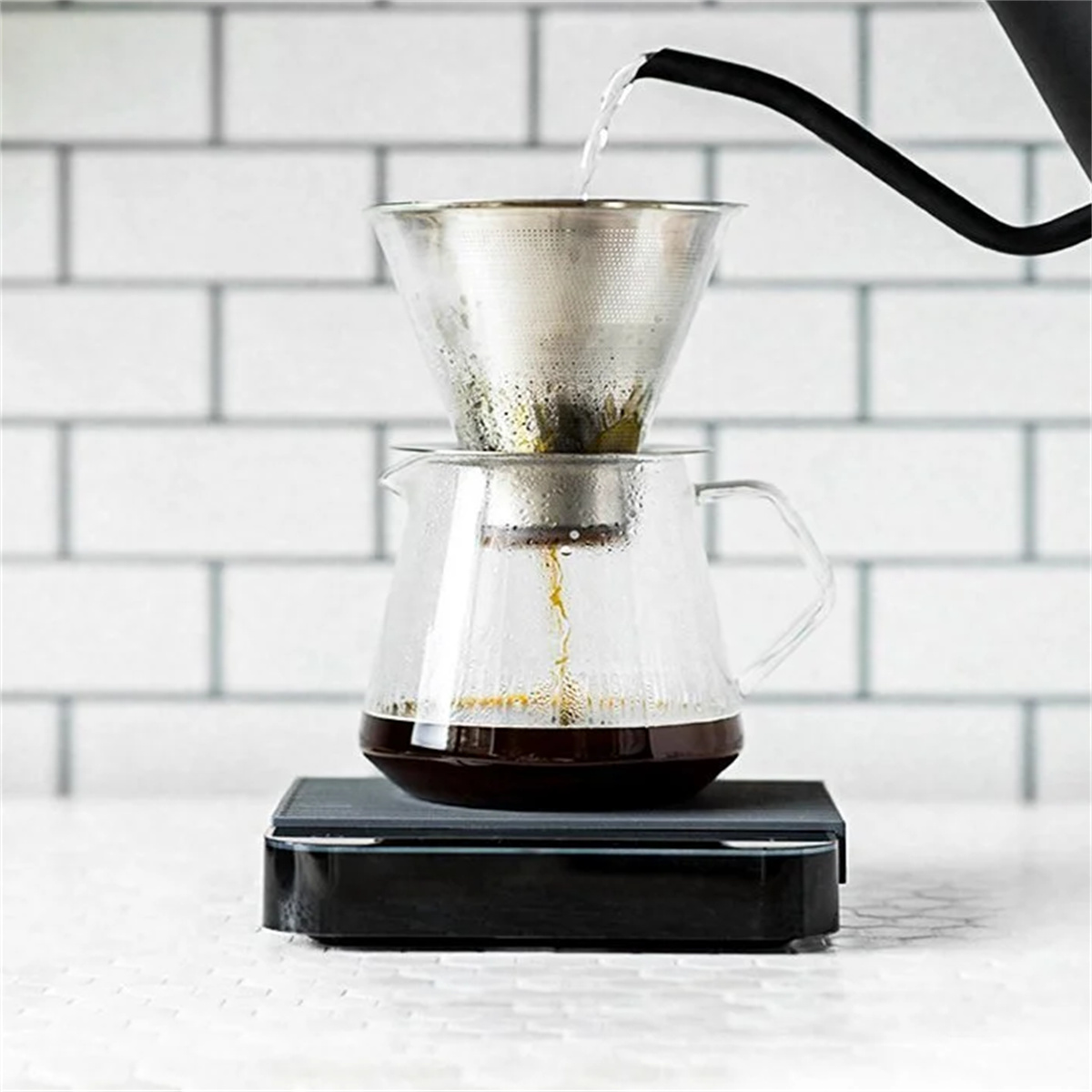 Gießen von Wasser durch einen Kaffeefilter in eine Glaskaraffe auf einer Waage.