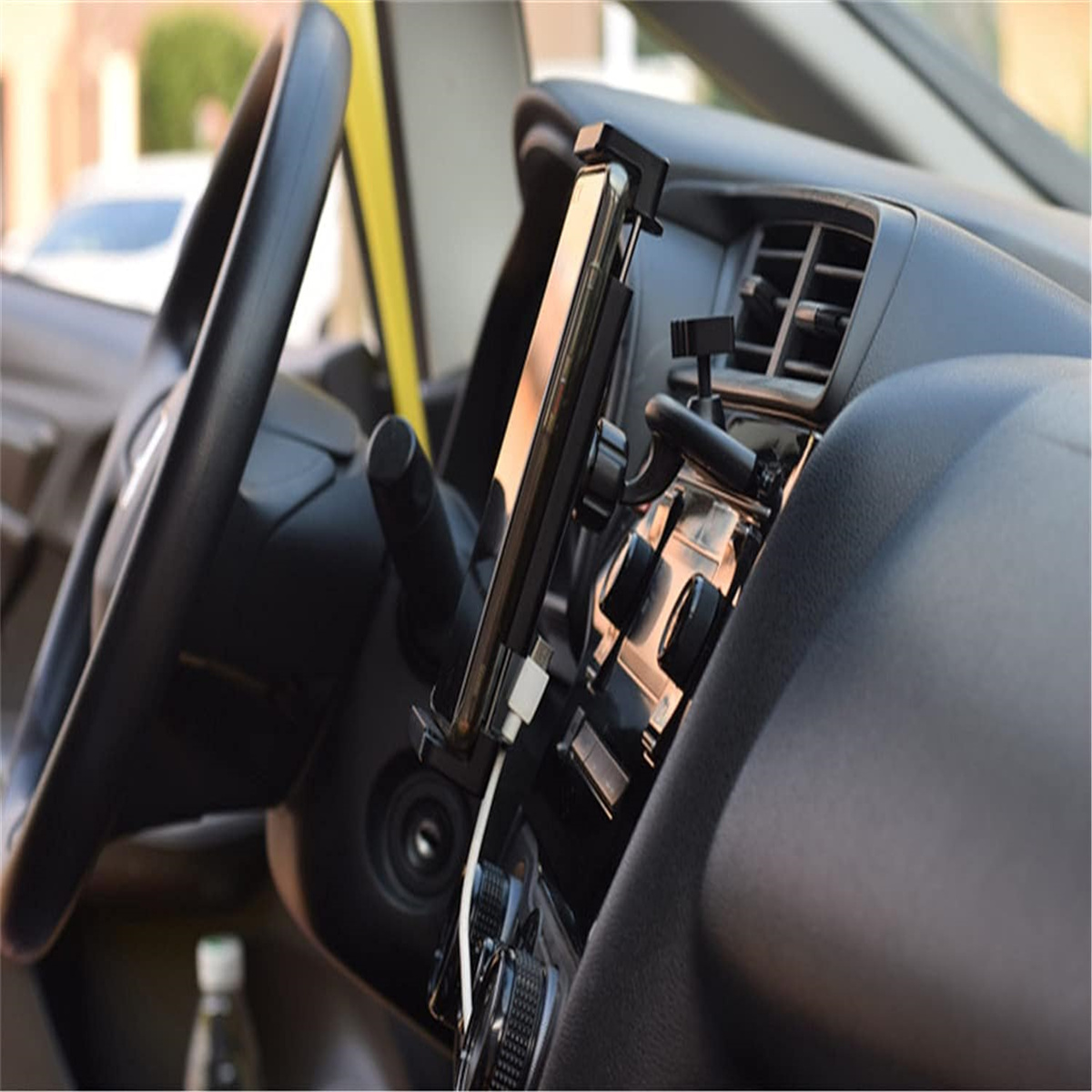 Innenraum eines Autos, Telefon in einer Halterung auf dem Armaturenbrett. Lenkrad und Knöpfe sind sichtbar.