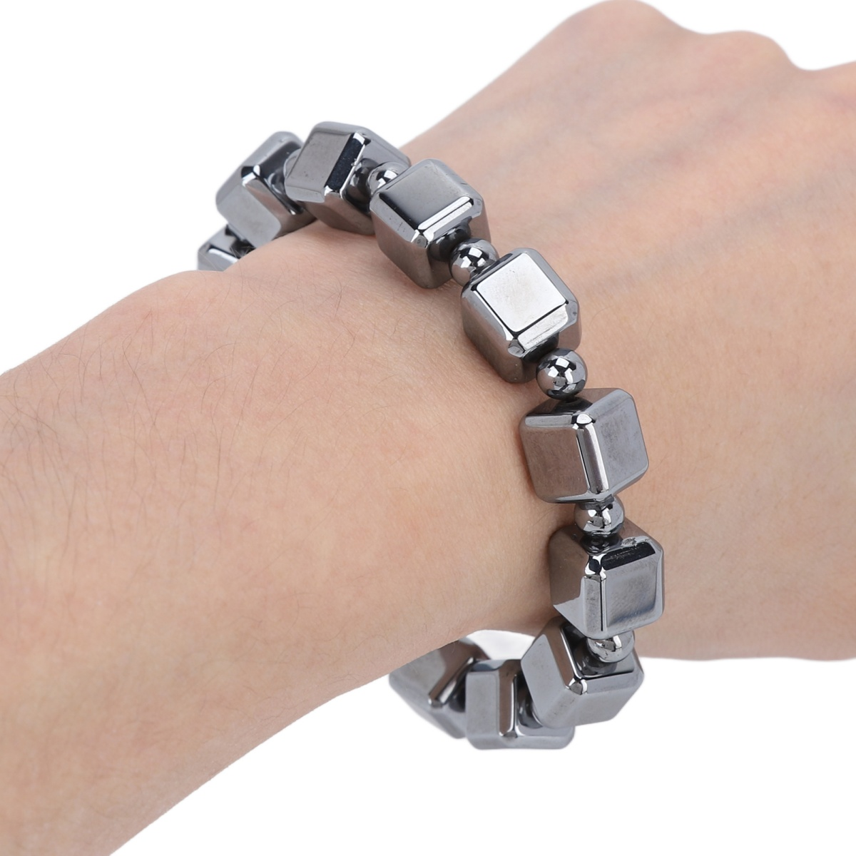 Eine Hand, die ein Armband aus dunklen, würfelförmigen Perlen trägt.