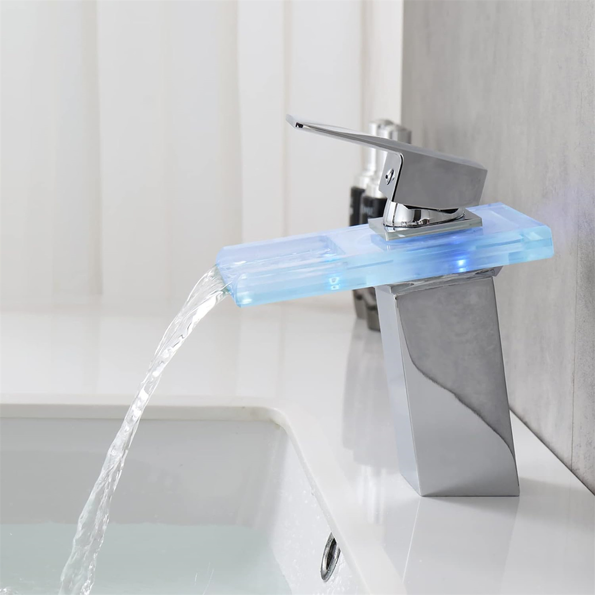 Chrom-Wasserhahn. Wasser fließt. Blau beleuchtetes Glas. Weißes Waschbecken und Hintergrund. Modernes Design.