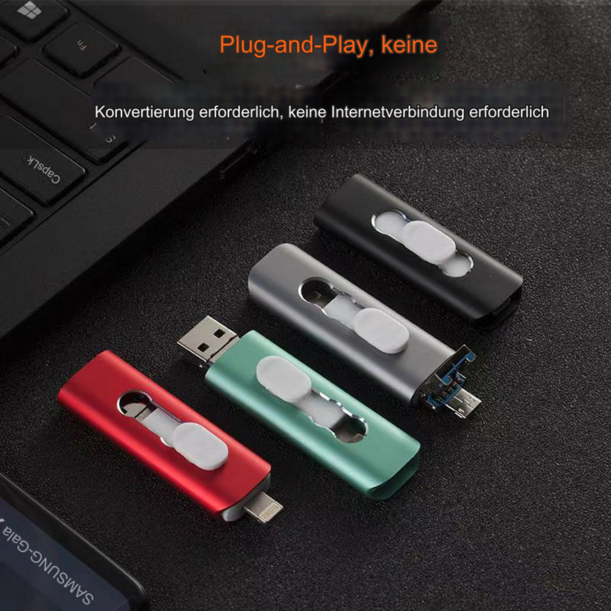 Vier USB-Laufwerke in verschiedenen Farben. Sie befinden sich auf einer Oberfläche neben einer Tastatur.