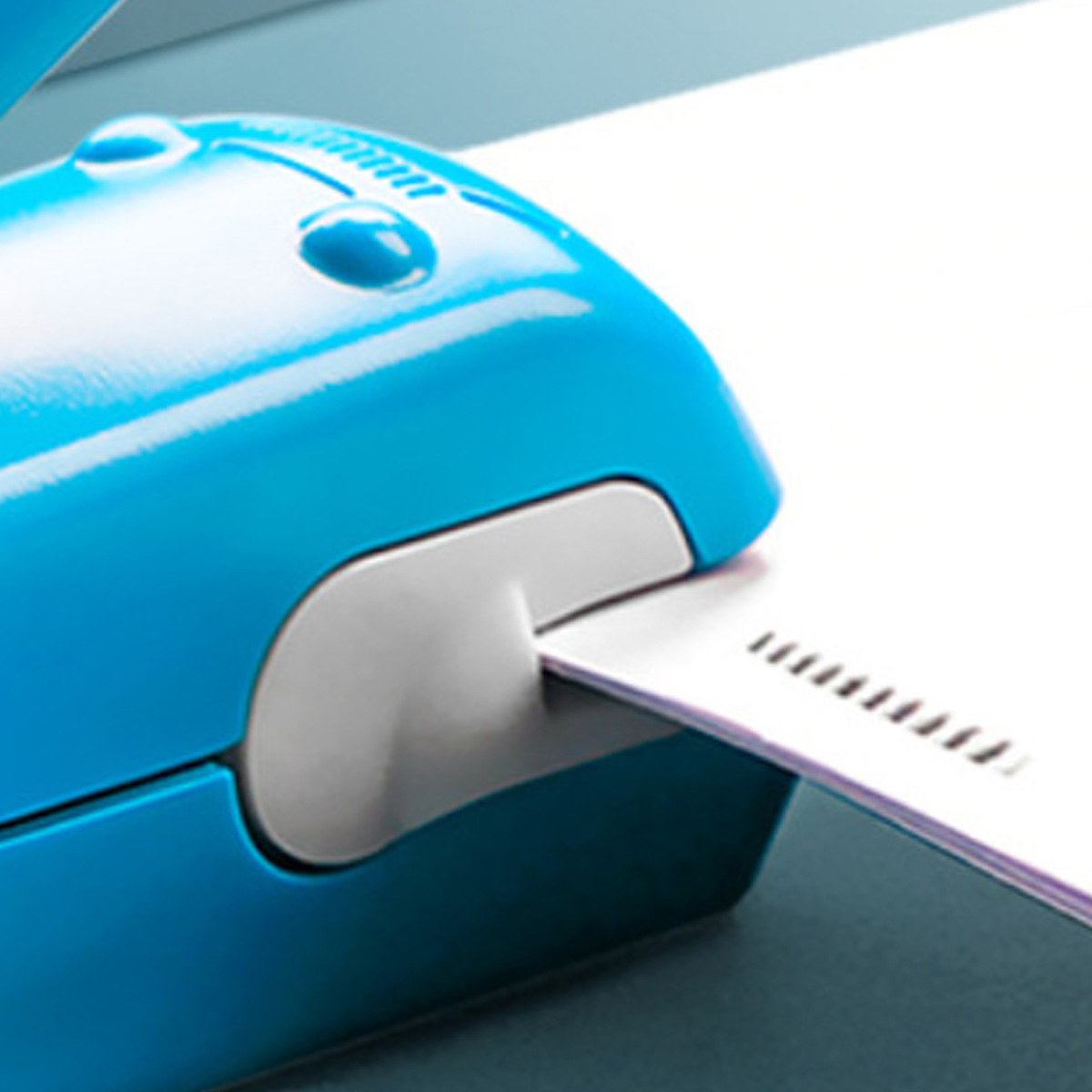 Blauer Tacker mit weißem Papier. Das Bild ist eine Nahaufnahme.