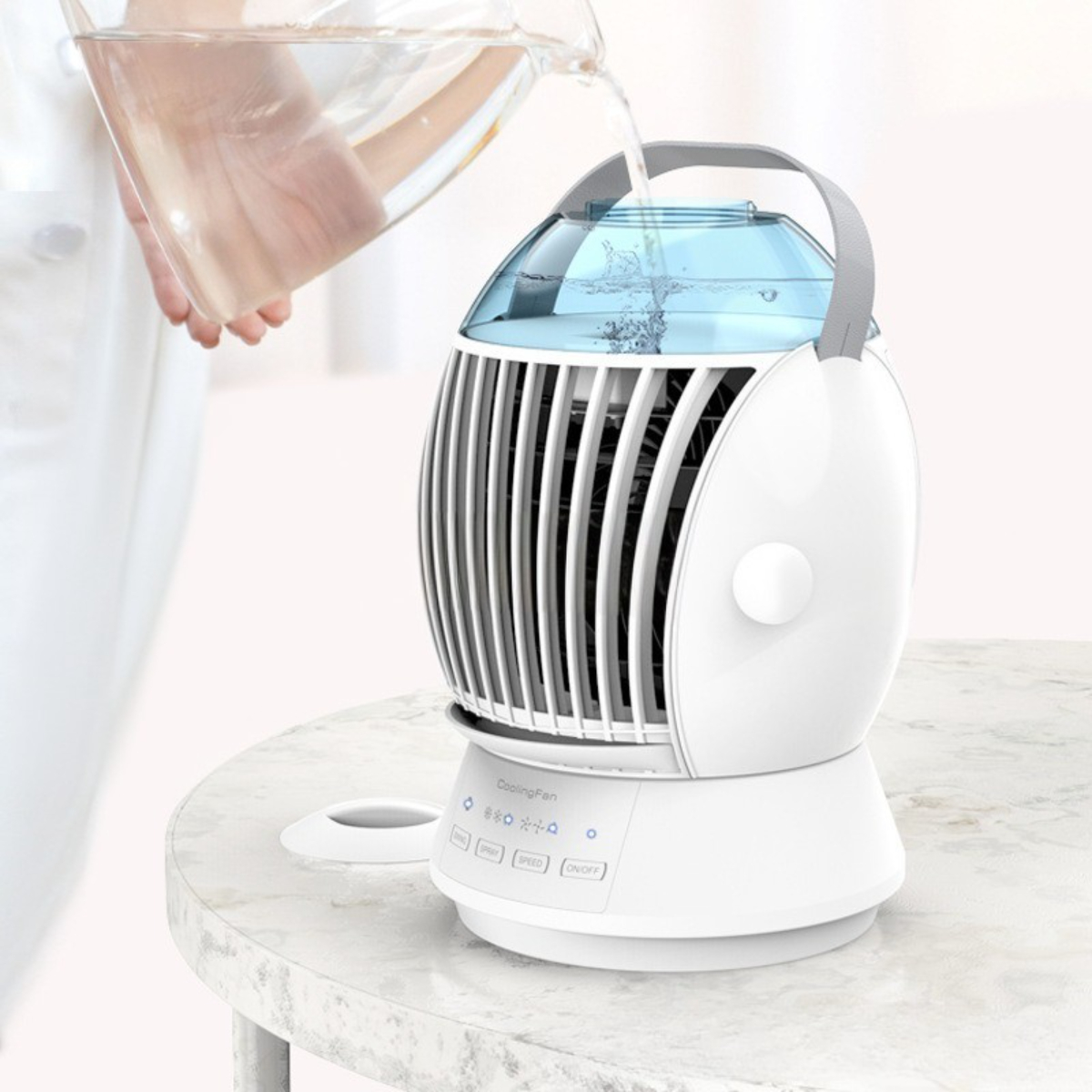 Eine Person gießt Wasser in einen weißen Ventilator auf einem Tisch. Knöpfe und Wasser sichtbar.