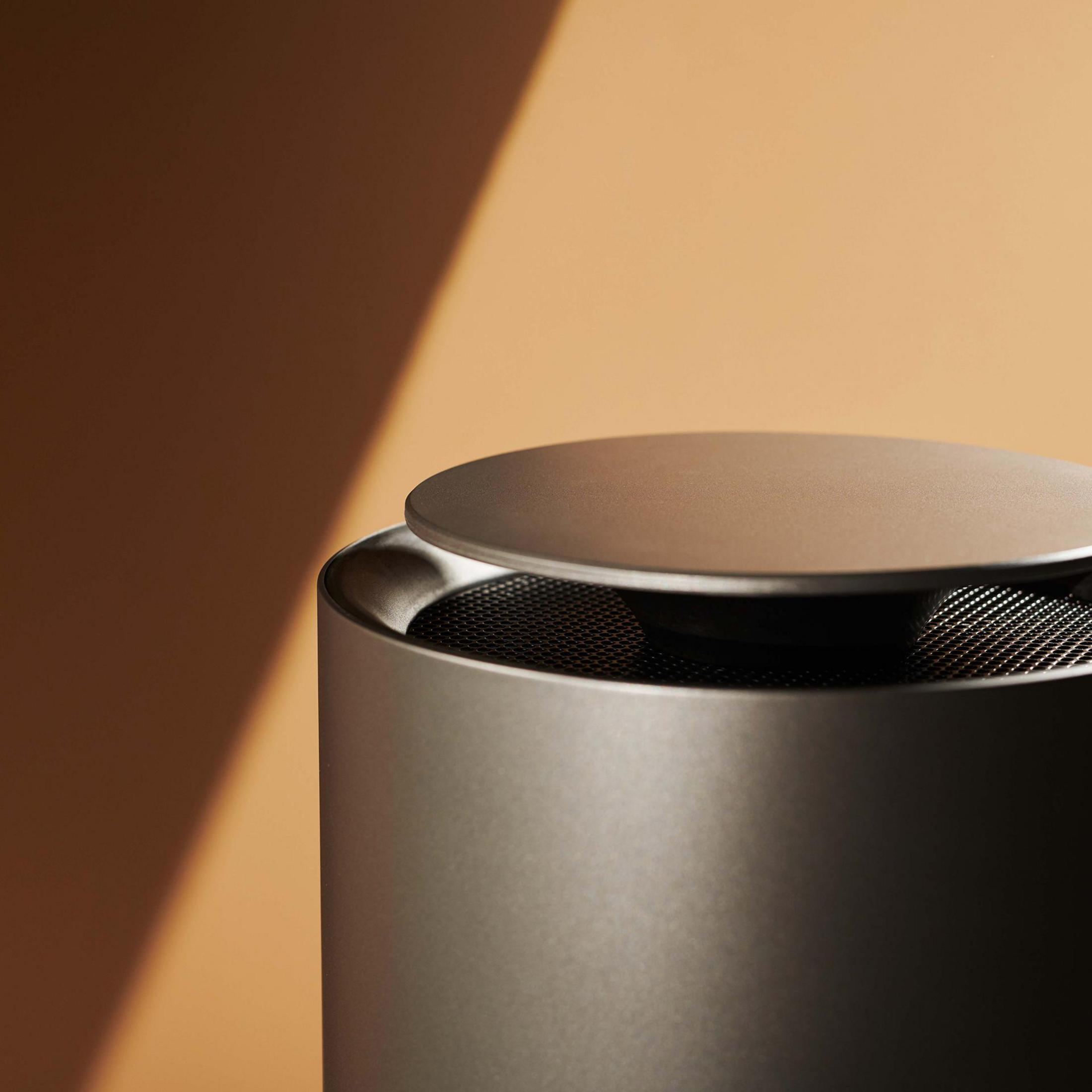 Metalowy głośnik z częściowo otwartą górą, rzucający cień.