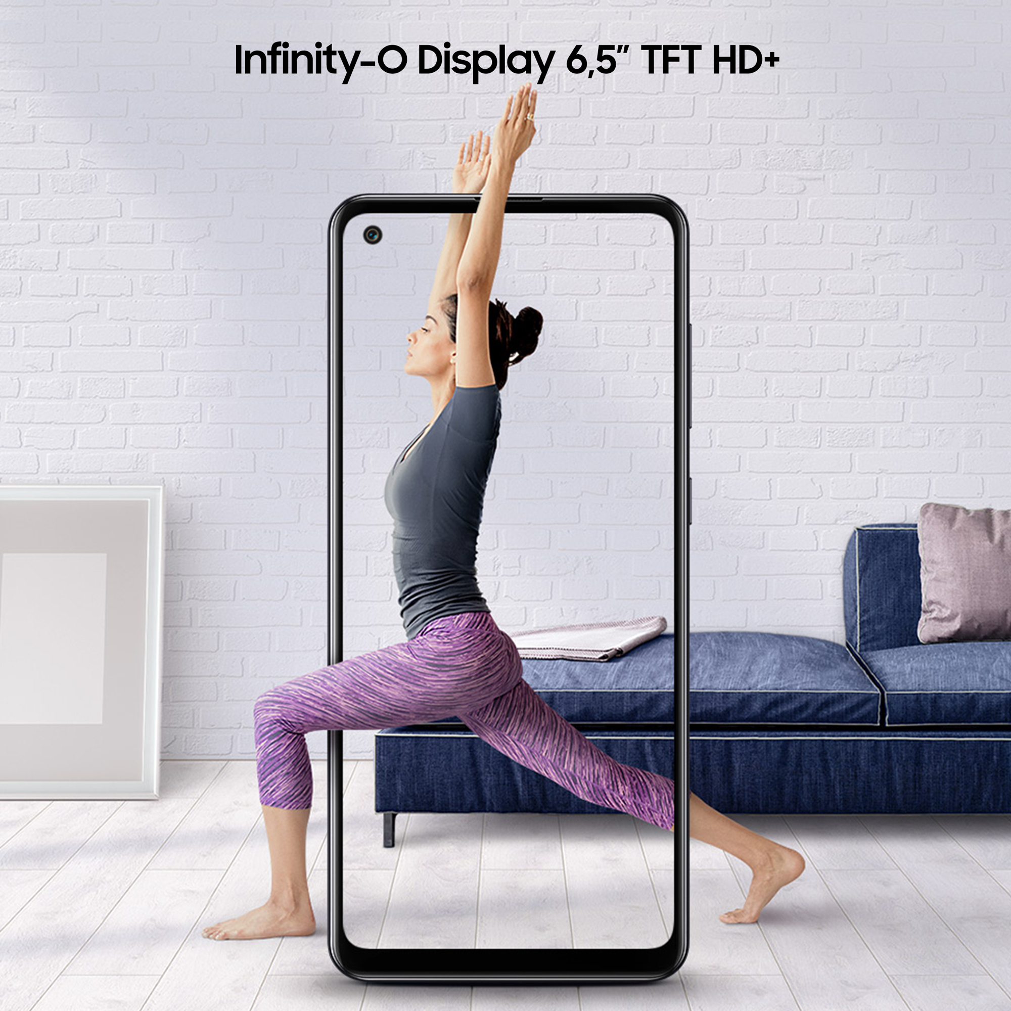 Kobieta w pozycji jogi jest pokazana na ekranie telefonu. Ekran jest w pokoju z białymi ceglanymi ścianami.