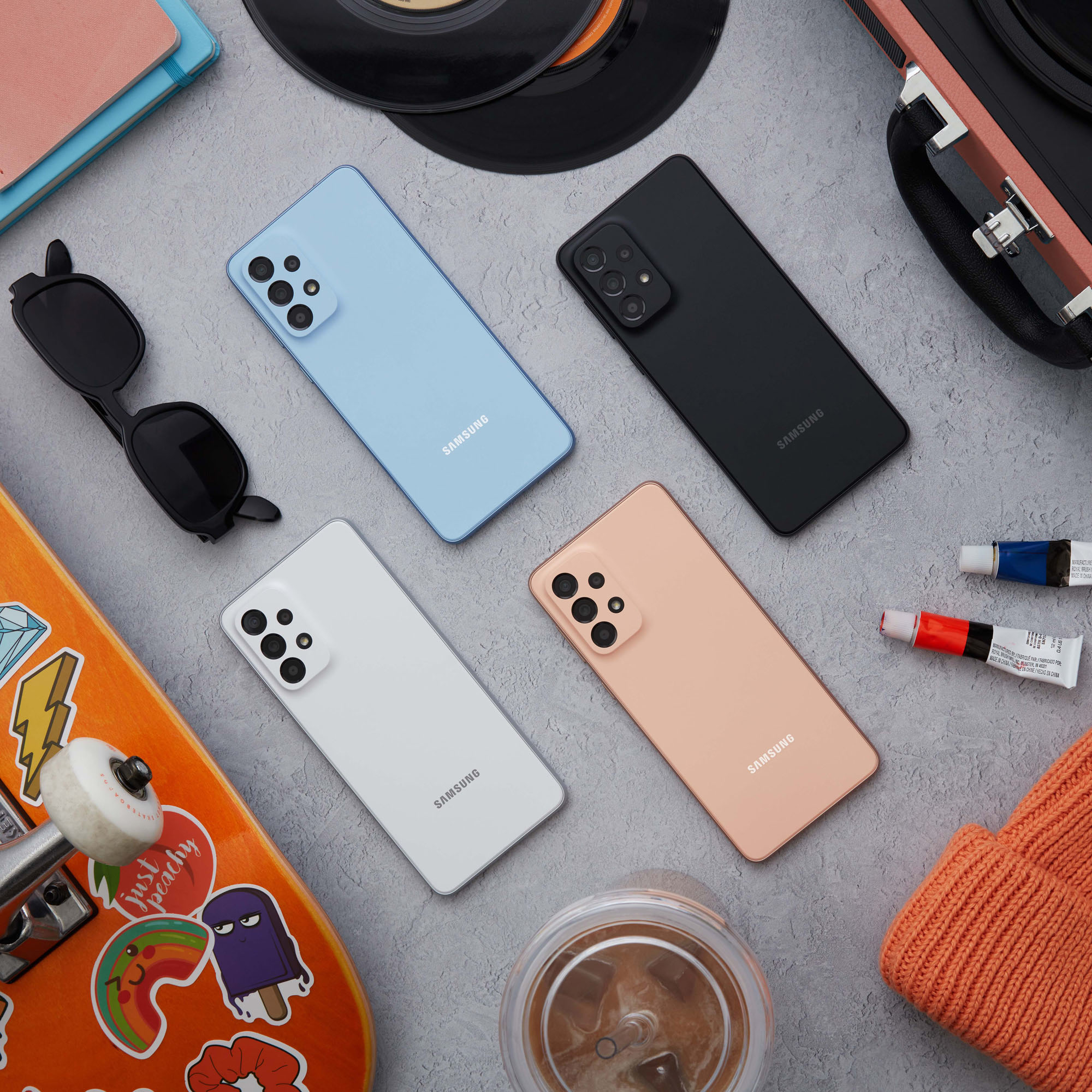 Układ płaski telefonów, deskorolki, okularów przeciwsłonecznych, materiałów artystycznych, płyt winylowych i kapelusza.