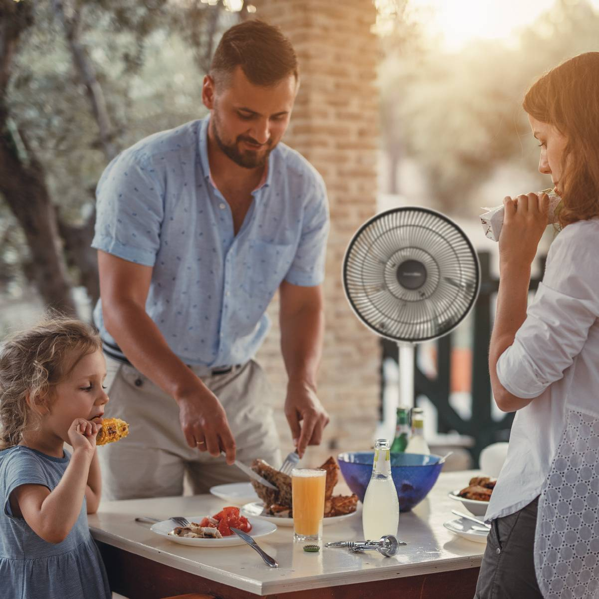 Familia comiendo en una mesa. Un ventilador está en la mesa.