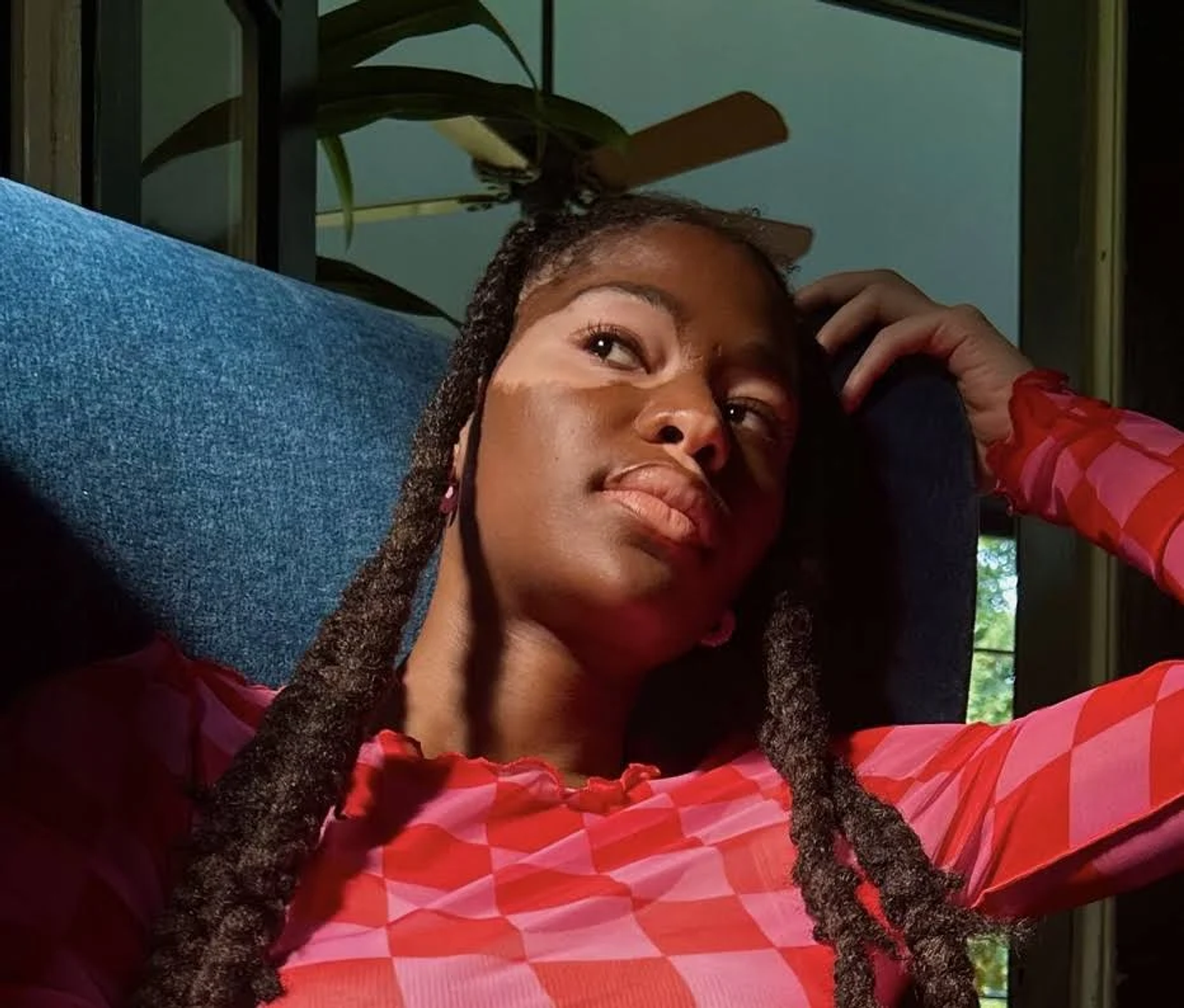 Kobieta z bielactwem w czerwonym i różowym topie, patrząca w górę.