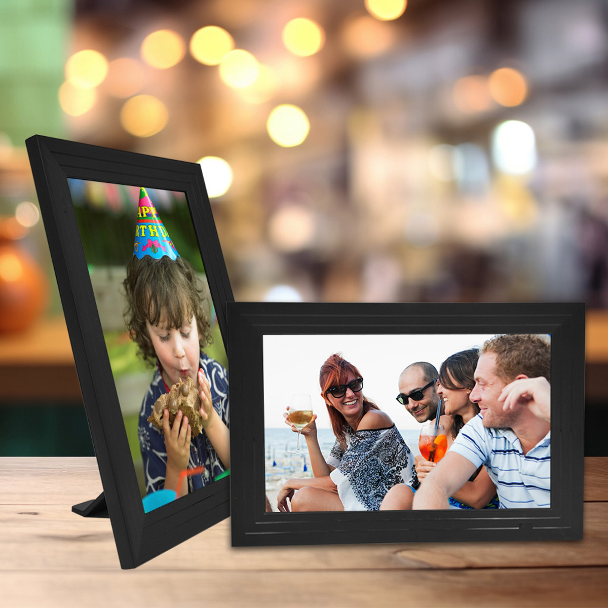 Dwie czarne ramki na zdjęcia na drewnianym stole. Jedna pokazuje dziecko, druga grupę osób.