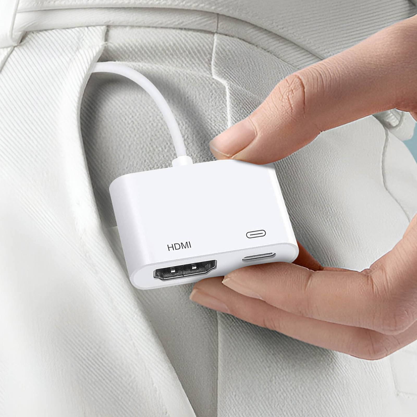 Ein weißer HDMI-Adapter, gehalten von einer Person, mit HDMI, USB-C und SD-Karten-Ports.