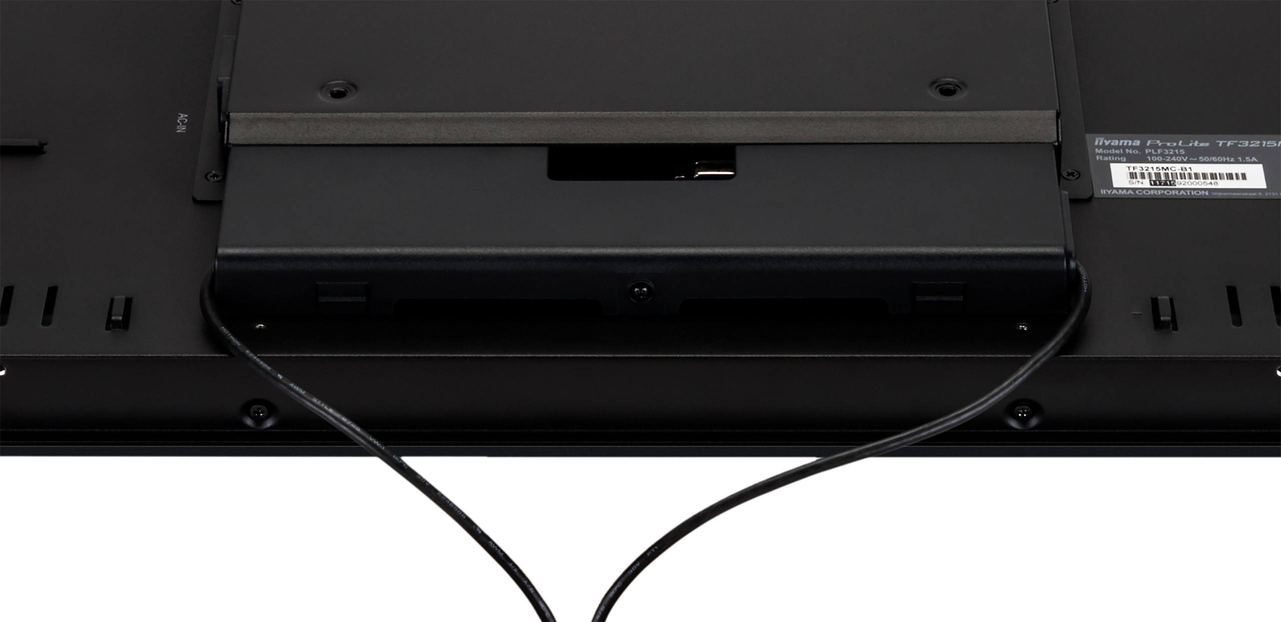 Tył czarnego monitora. Widoczne kable i złącza. Białe tło.