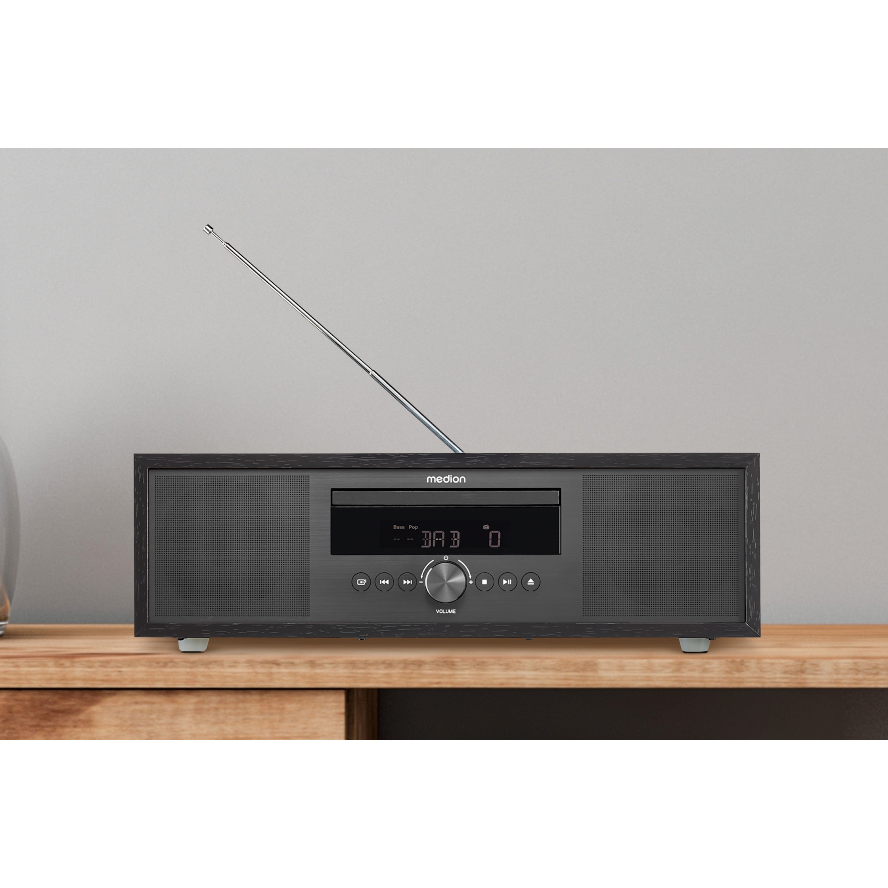 Zwart stereosysteem op een houten tafel. Het heeft een cd-speler en een radioantenne.