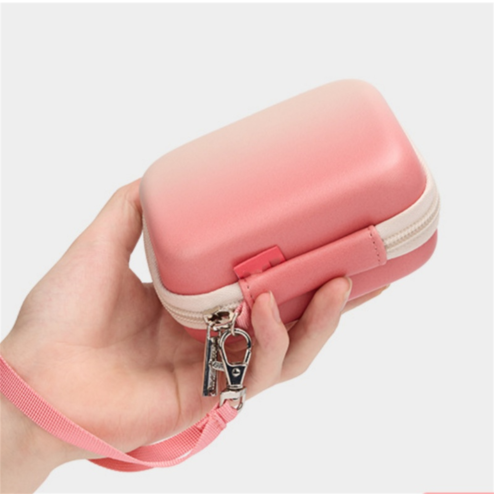 Ein kleines rosa Etui mit Griff und Reißverschluss wird von einer Hand mit einem rosa Schlüsselband gehalten.