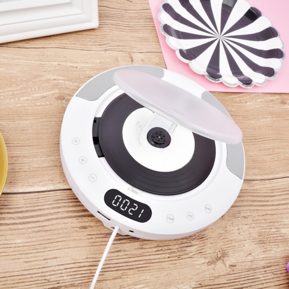 Weißer CD-Player mit einer schwarzen CD im Inneren und einem Digitaldisplay. Es steht auf einem Holztisch.
