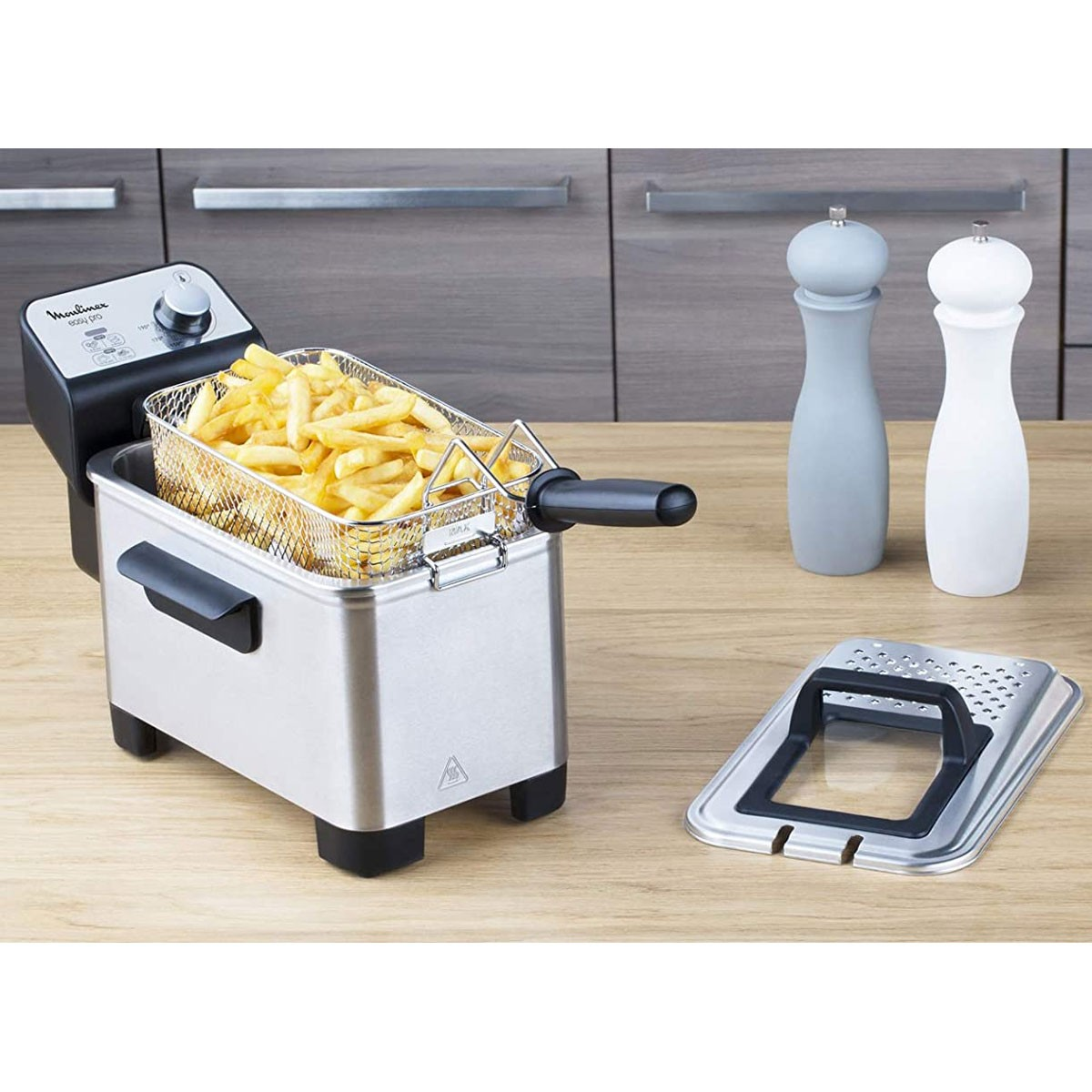 RVS friteuse met friet. Twee zout- en peperstrooiers en een deksel.