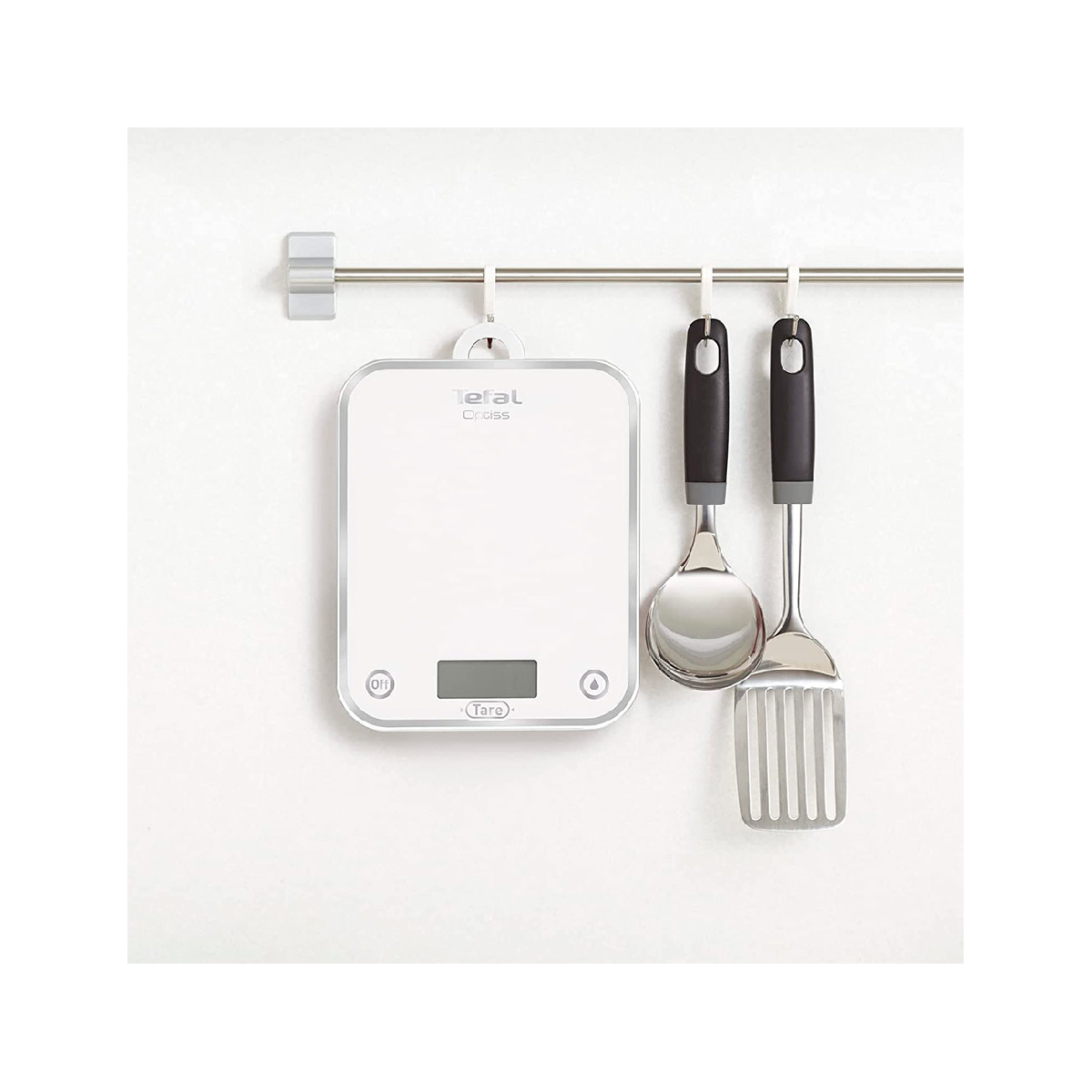 Waga kuchenna, szpatułka i chochla wiszące na ścianie.