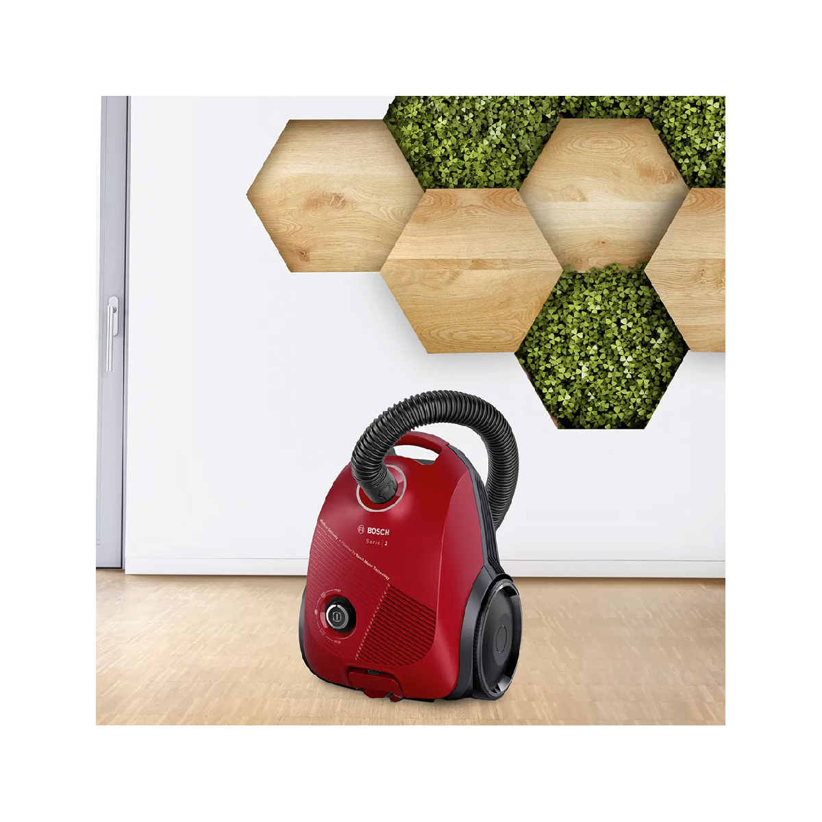 Czerwony odkurzacz Bosch na drewnianej podłodze, z dekoracją ścienną.