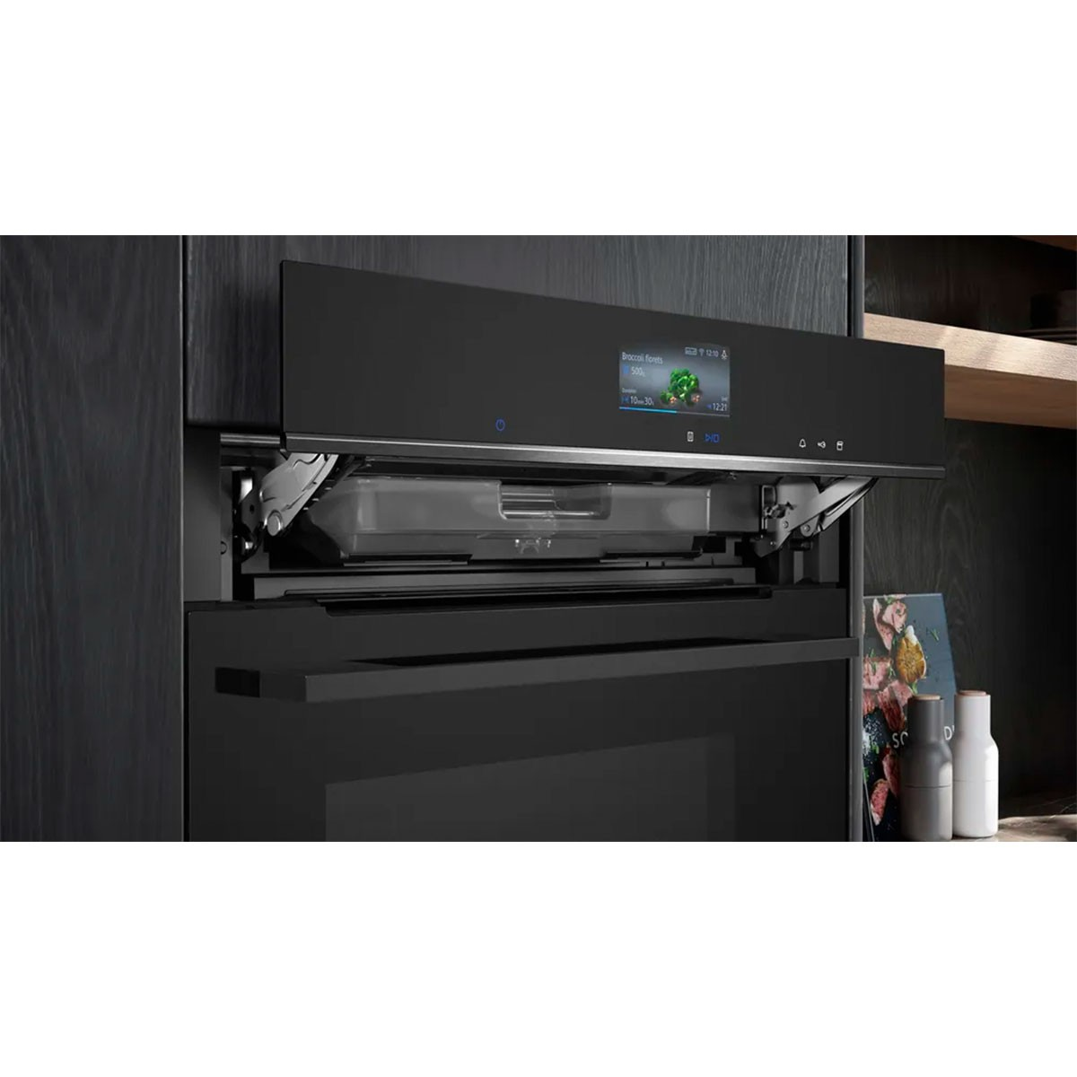 Een zwarte oven met een digitaal display met broccoli. Het is ingebouwd in een donkere houten kast. Er staan flessen rechts.