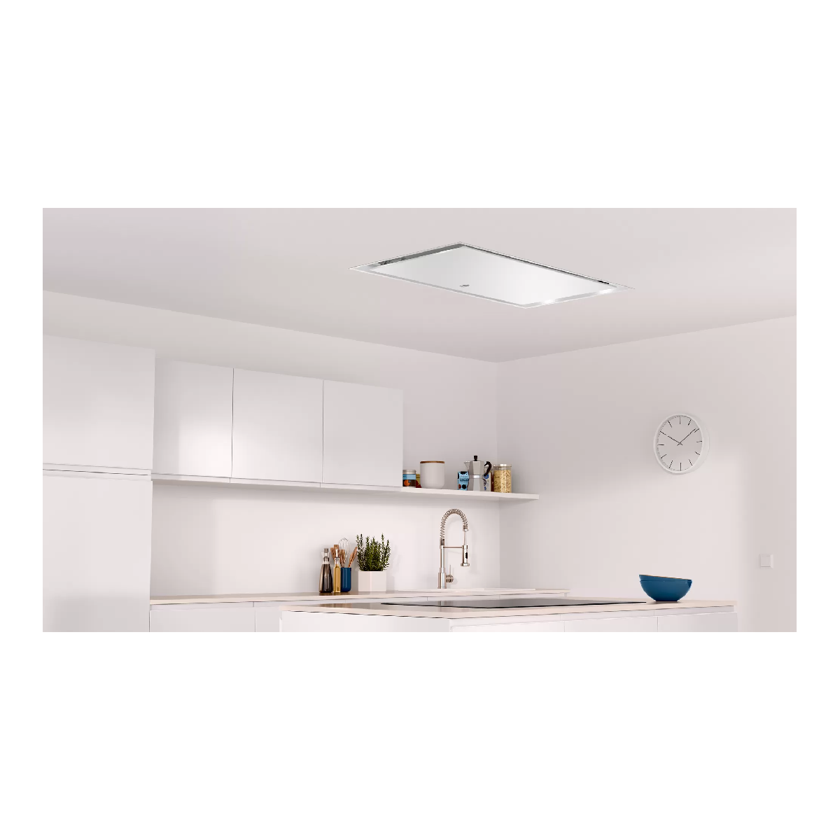 Una cocina con gabinetes blancos y una campana extractora montada en el techo. Reloj en la pared.
