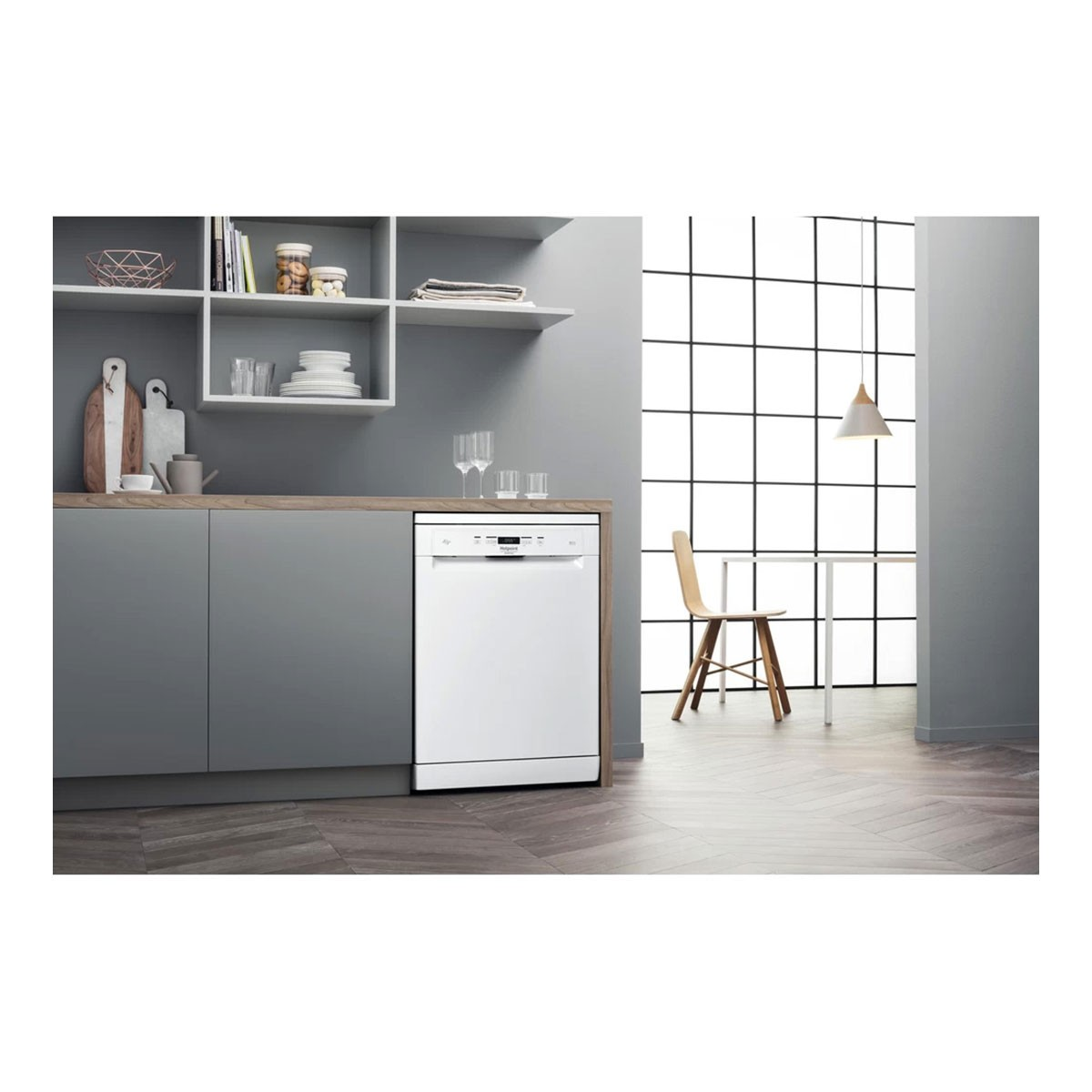 Un lavavajillas blanco en una cocina con encimera de madera, estantes con platos y una ventana grande.