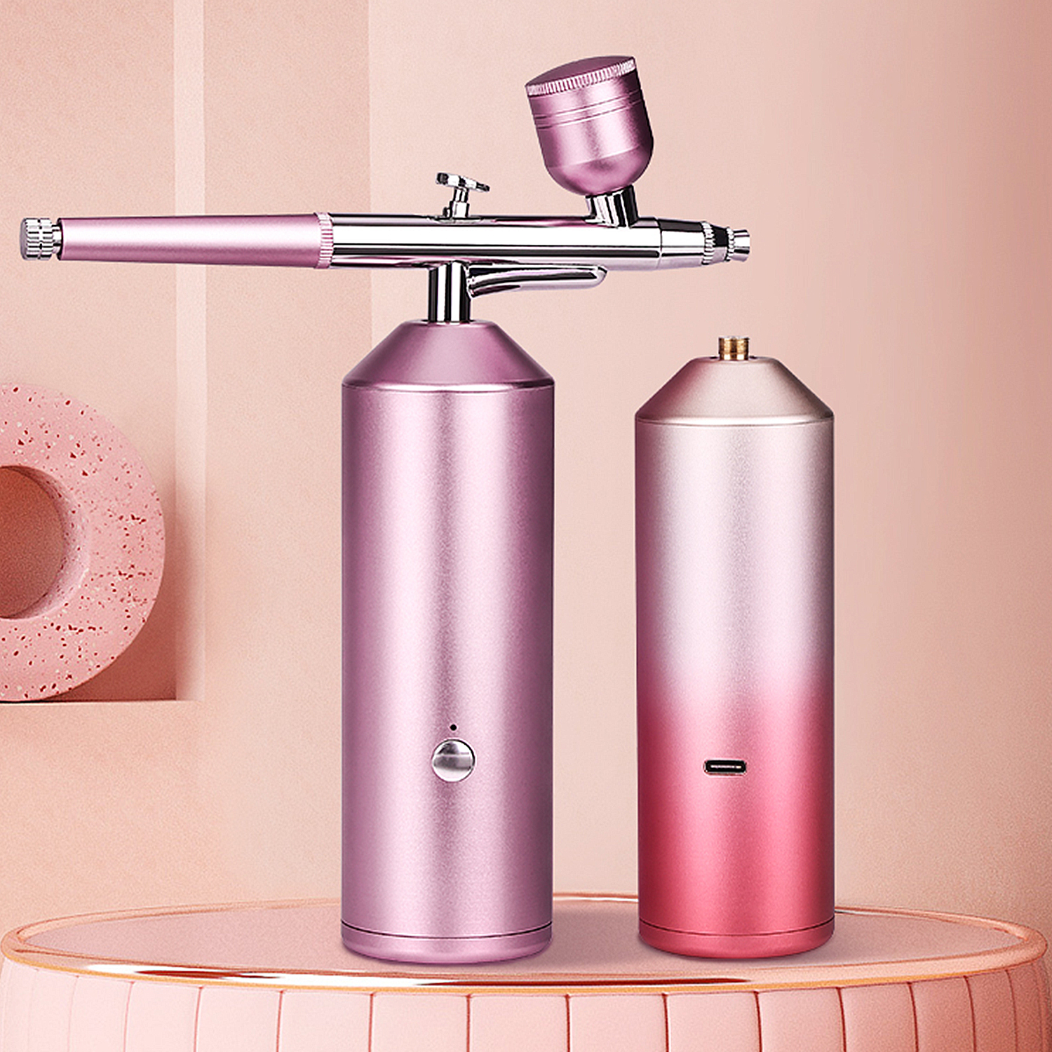 Kit aerografo rosa e un piccolo contenitore rosa. Su un piedistallo rosa con sfondo rosa.
