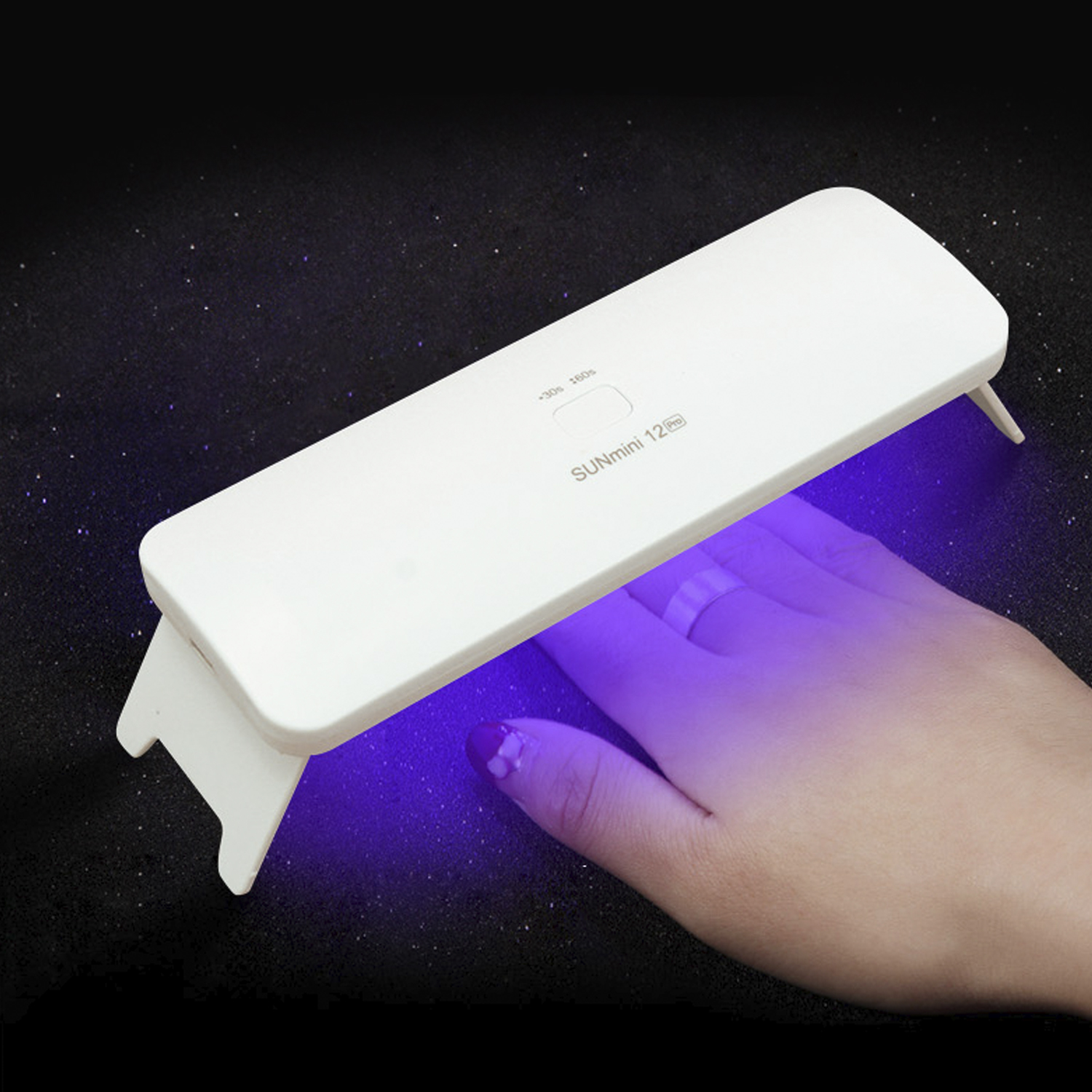 Una mano sotto una lampada UV bianca per unghie con luce viola.