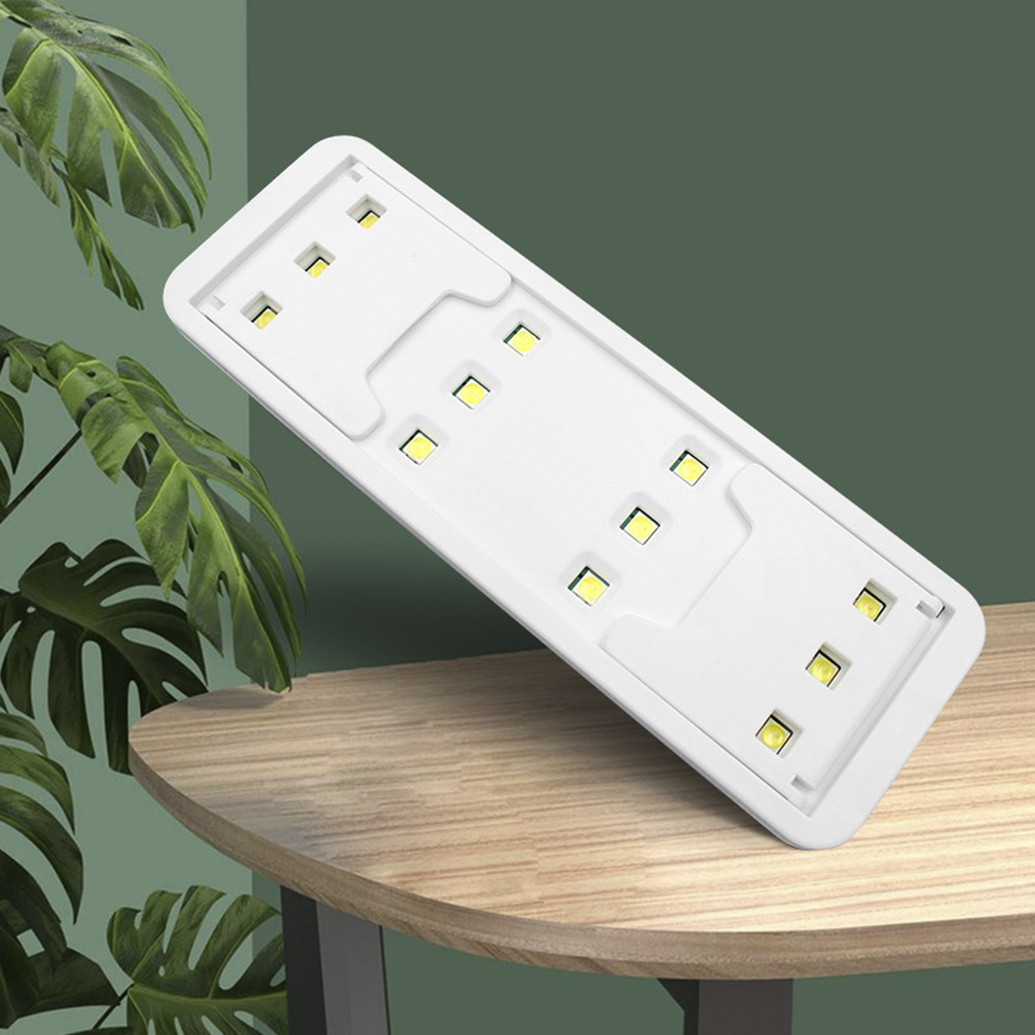 Pannello luminoso a LED rettangolare bianco, con sfondo verde e tavolo in legno.
