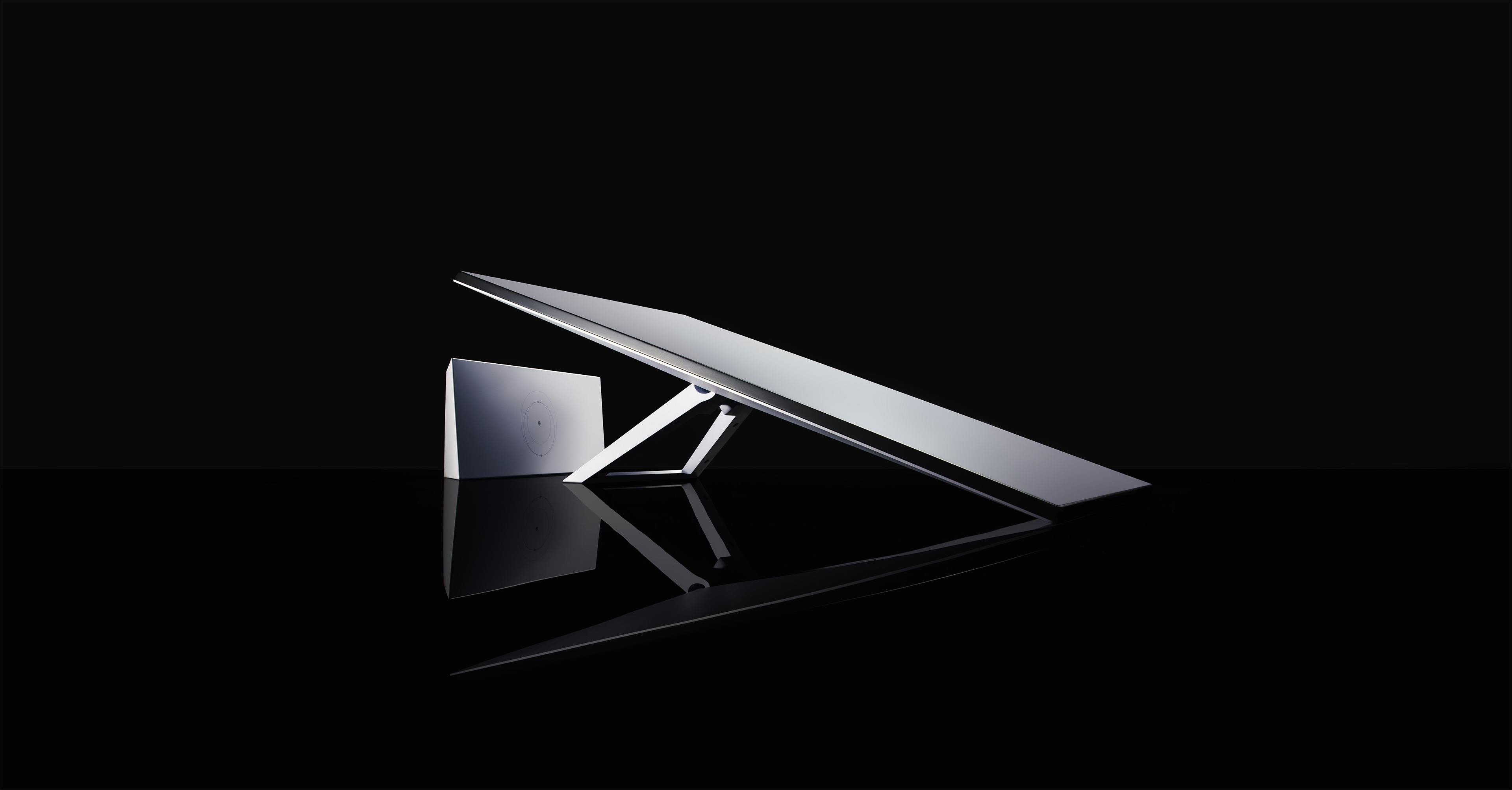 Ein moderner Monitor mit Sockel und separatem Lautsprecher. Schwarzer Hintergrund.