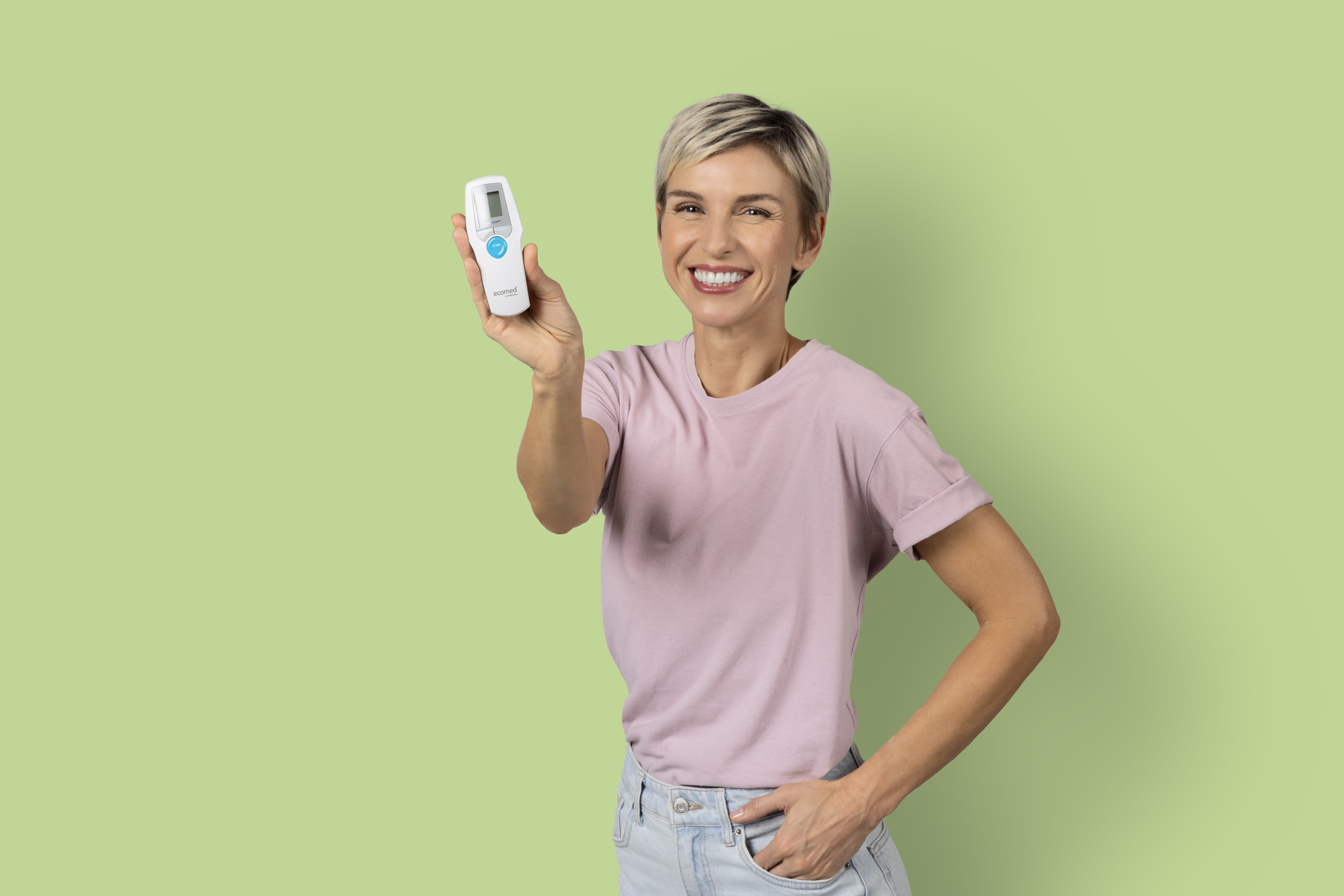 Woman holding a device, smiling at the camera against a green background.