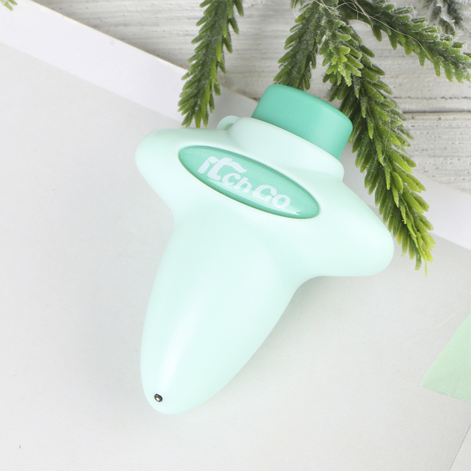 Dispositivo verde menta con logo, tapa verde, detalle planta verde.