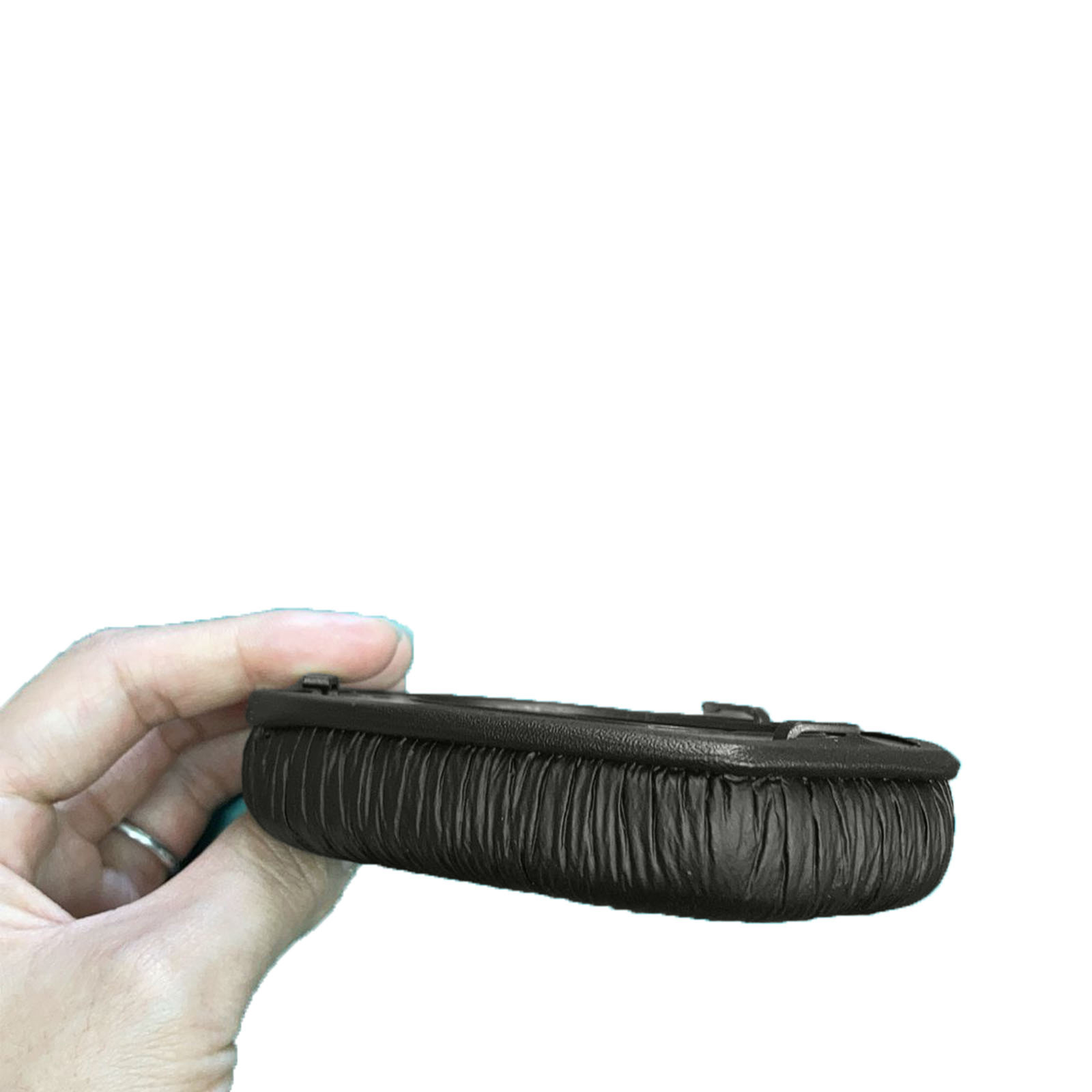 Osoba trzymająca ciemnobrązowy, owalny przedmiot, prawdopodobnie poduszkę do słuchawek.