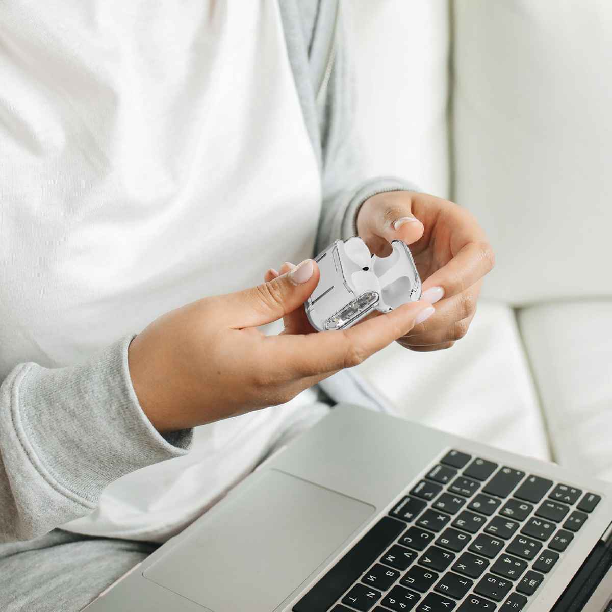Hände halten ein weißes und durchsichtiges Ladegerät, das mit einem Laptop verbunden ist, auf einer weißen Oberfläche.