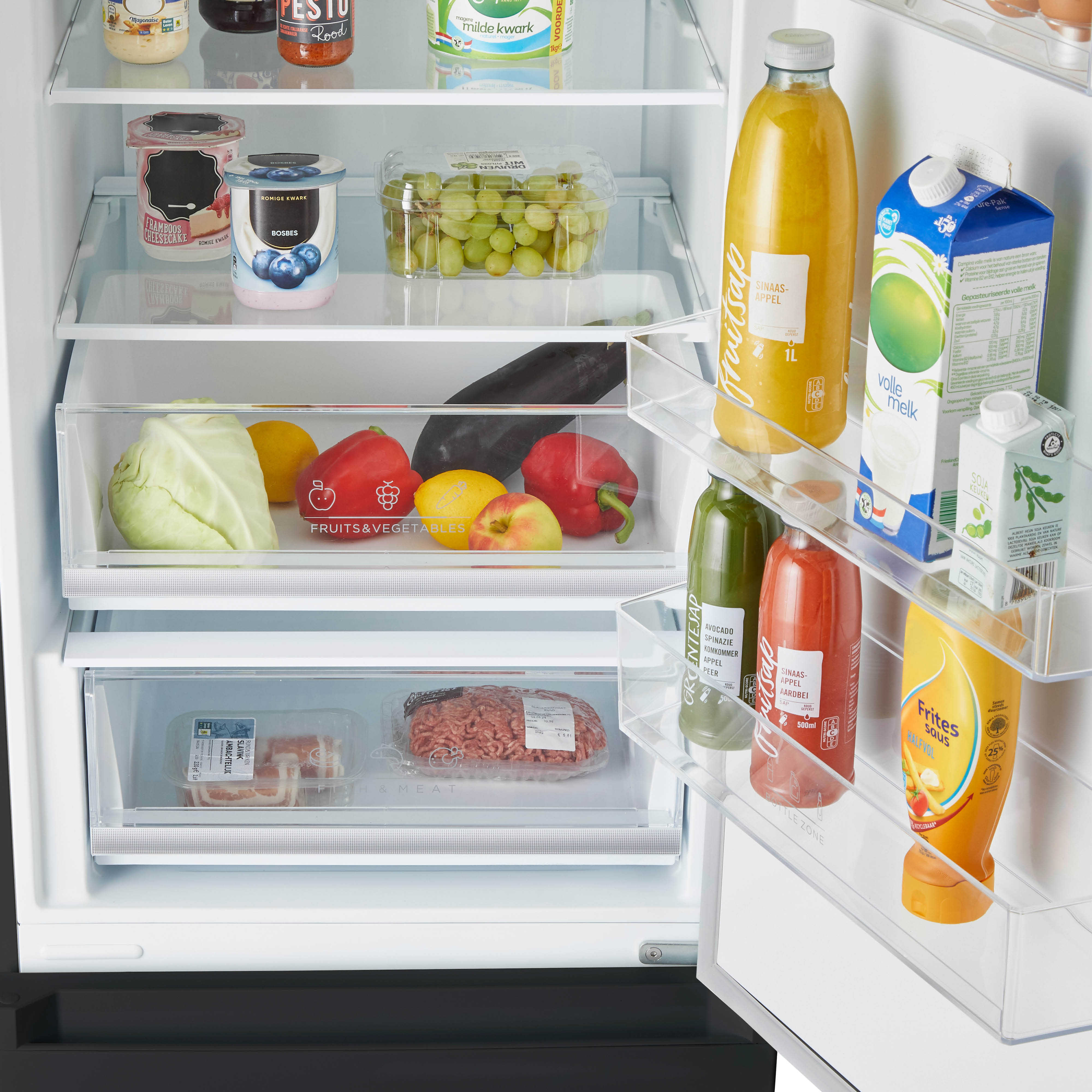 Refrigerator interior filled with fruits, vegetables, juices, and other food items.