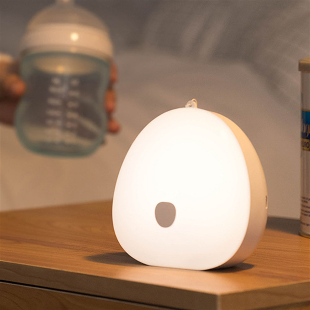 Weiß glühende Lampe auf einem Holztisch mit einer Flasche.