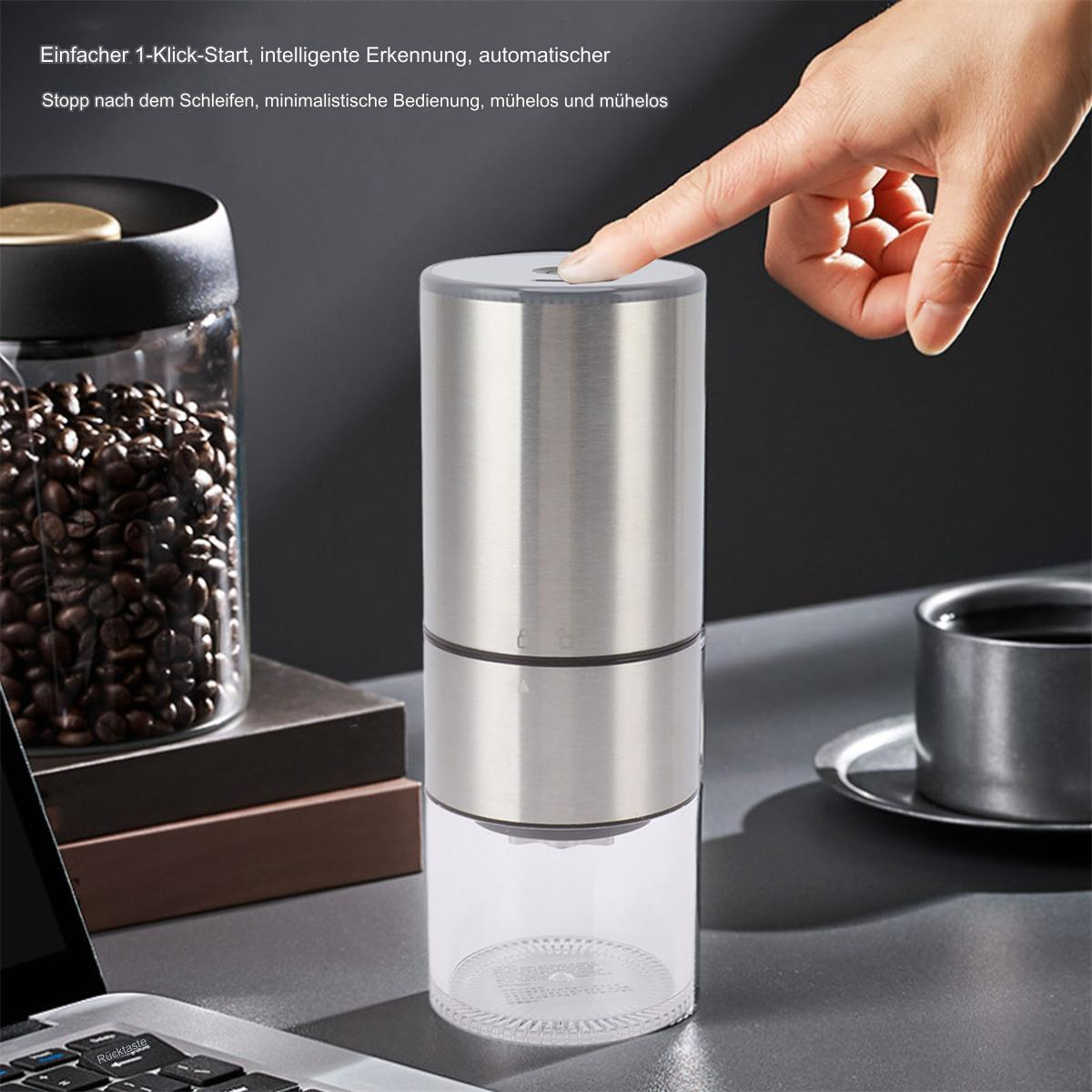 Eine Hand drückt einen Knopf auf einer silbernen und transparenten Kaffeemühle, mit Kaffeebohnen in einem Glas im Hintergrund.