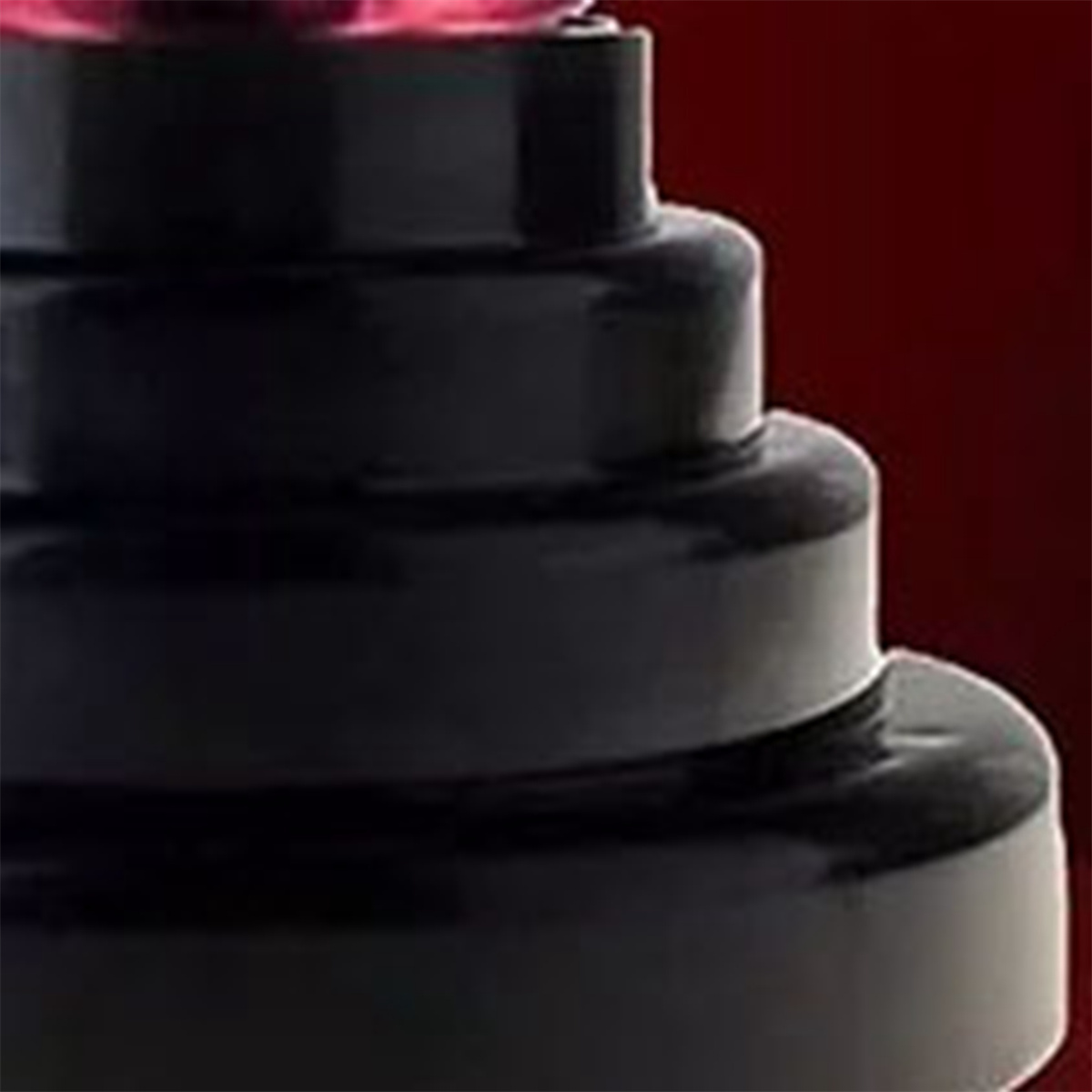 Schwarzes, gestuftes, zylindrisches Produkt mit rosa Spitze und verschwommenem Hintergrund.