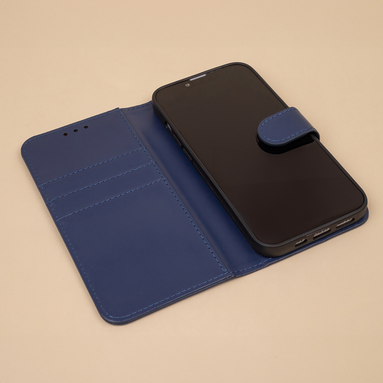 Offene blaue Handyhülle mit einem schwarzen Telefon darin. Beiger Hintergrund mit blauem Riemen.