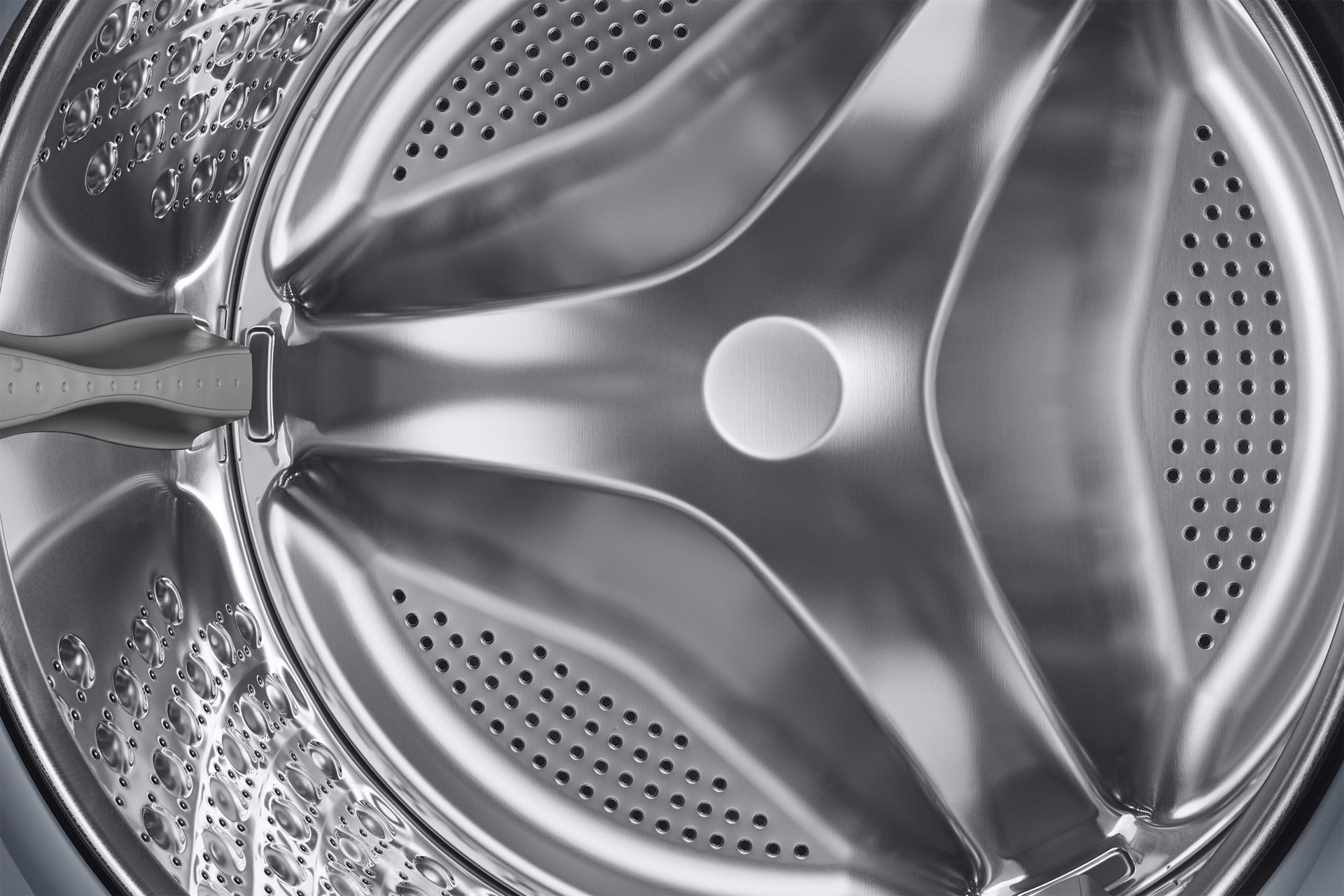 Wnętrze bębna pralki, srebrny kolor z otworami.