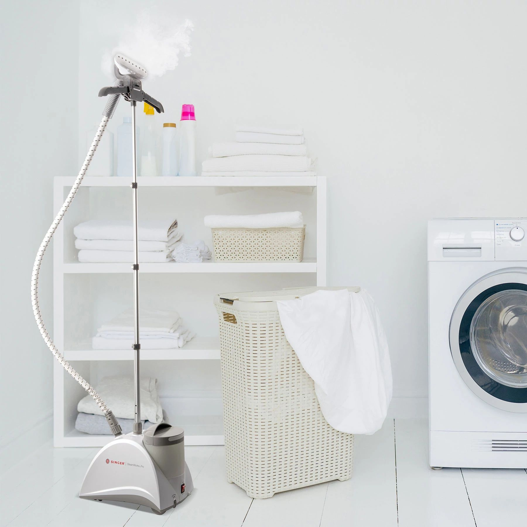 Laundry room with a clothes steamer, laundry basket, and a washing machine. White and clean.