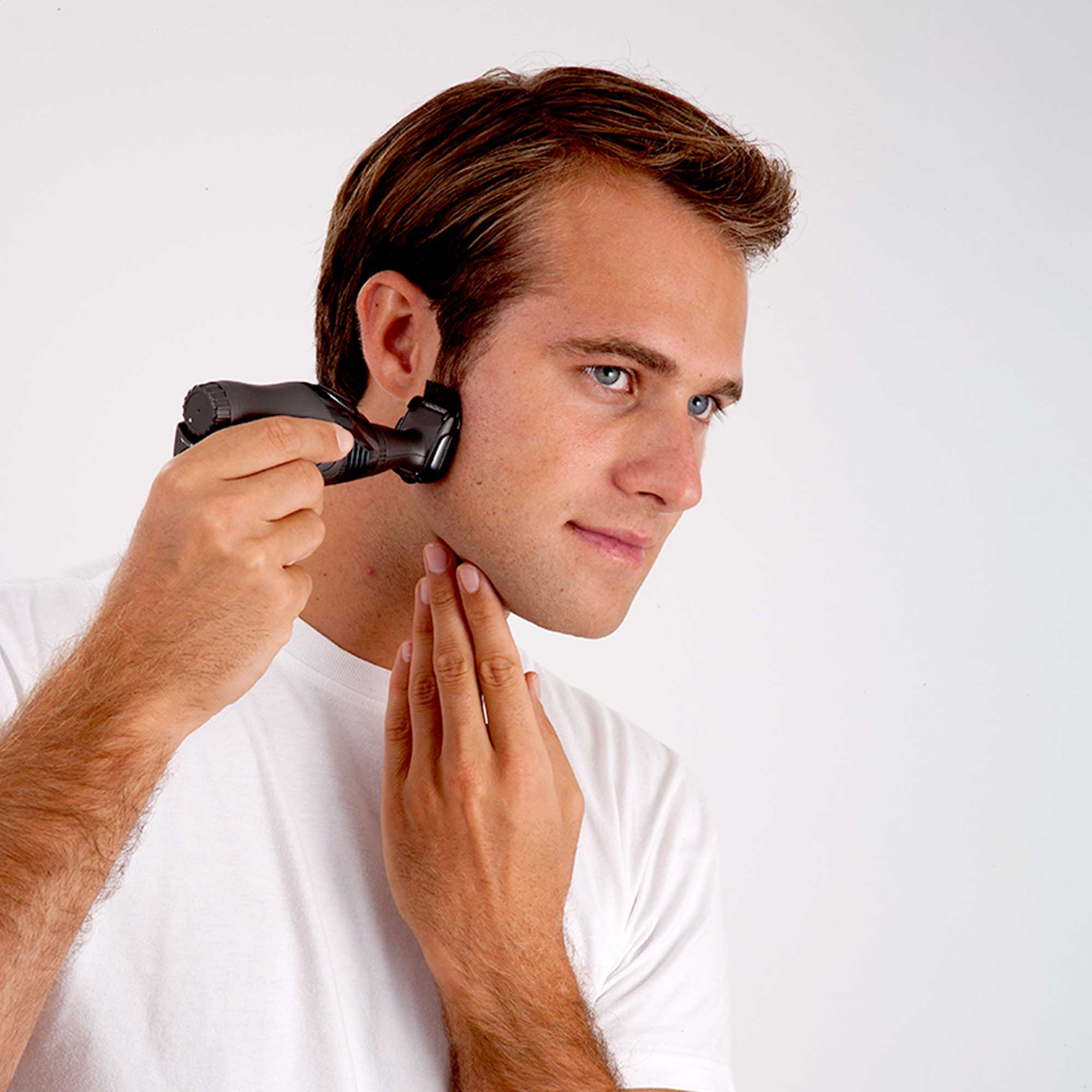 Man shaving his face with a black electric shaver, holding his skin with one hand.
