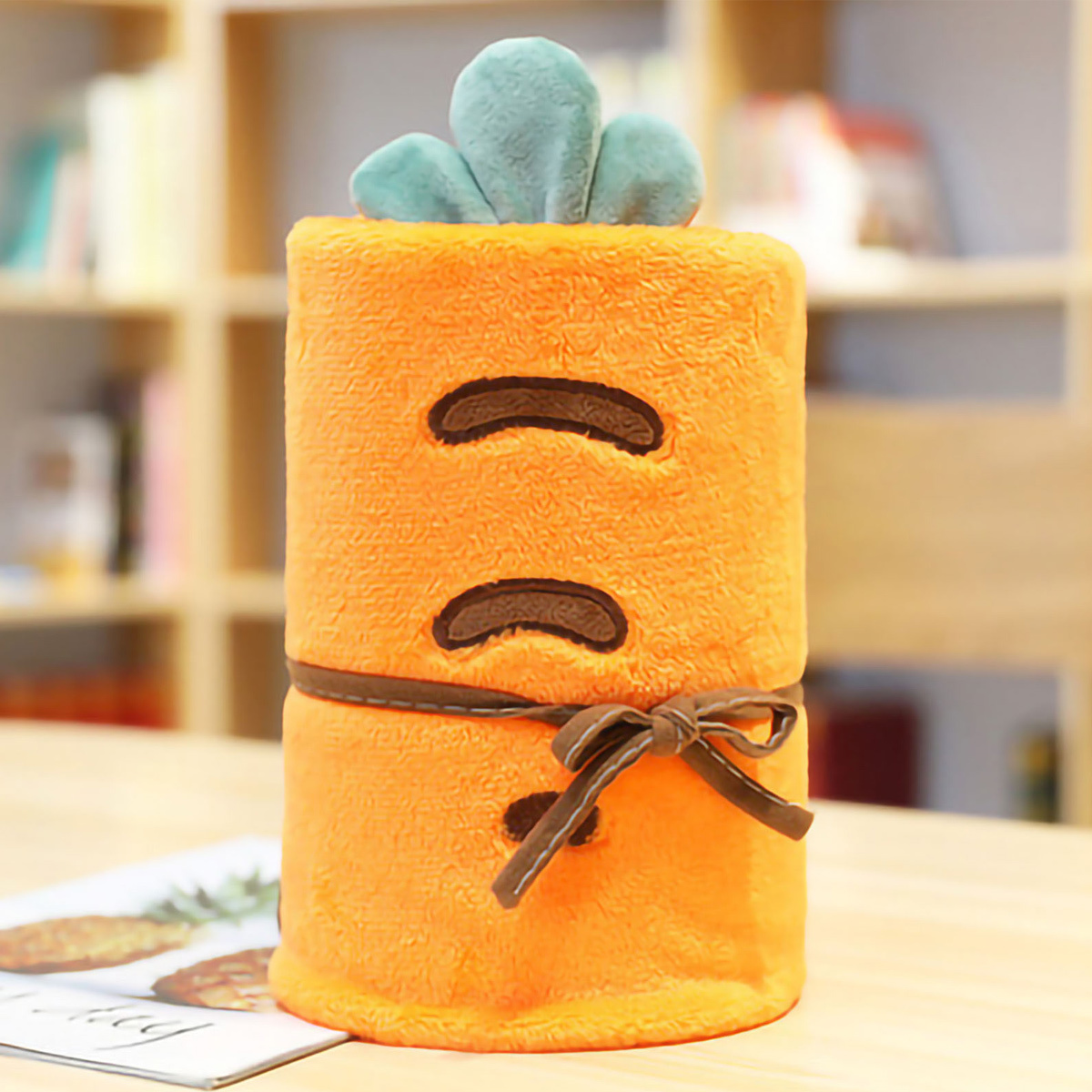 Orangenes karottenförmiges Plüschtier mit grünem Blätteraufsatz. Hat zwei Augen und eine Schleife.